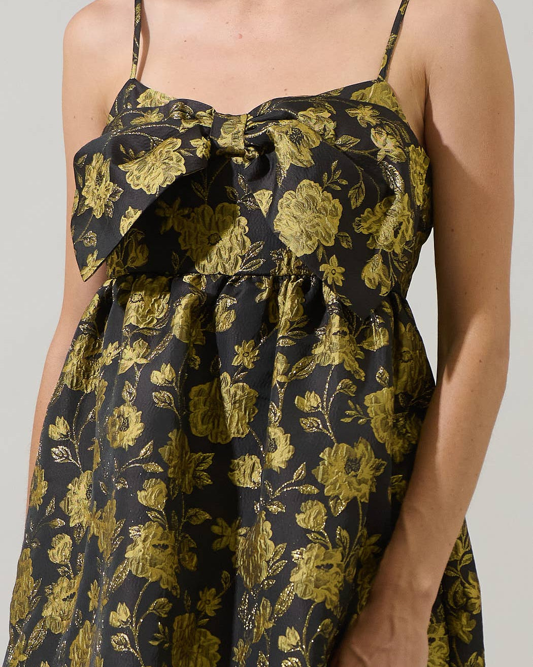 Woman wearing a black floral dress with yellow flowers on a plain background