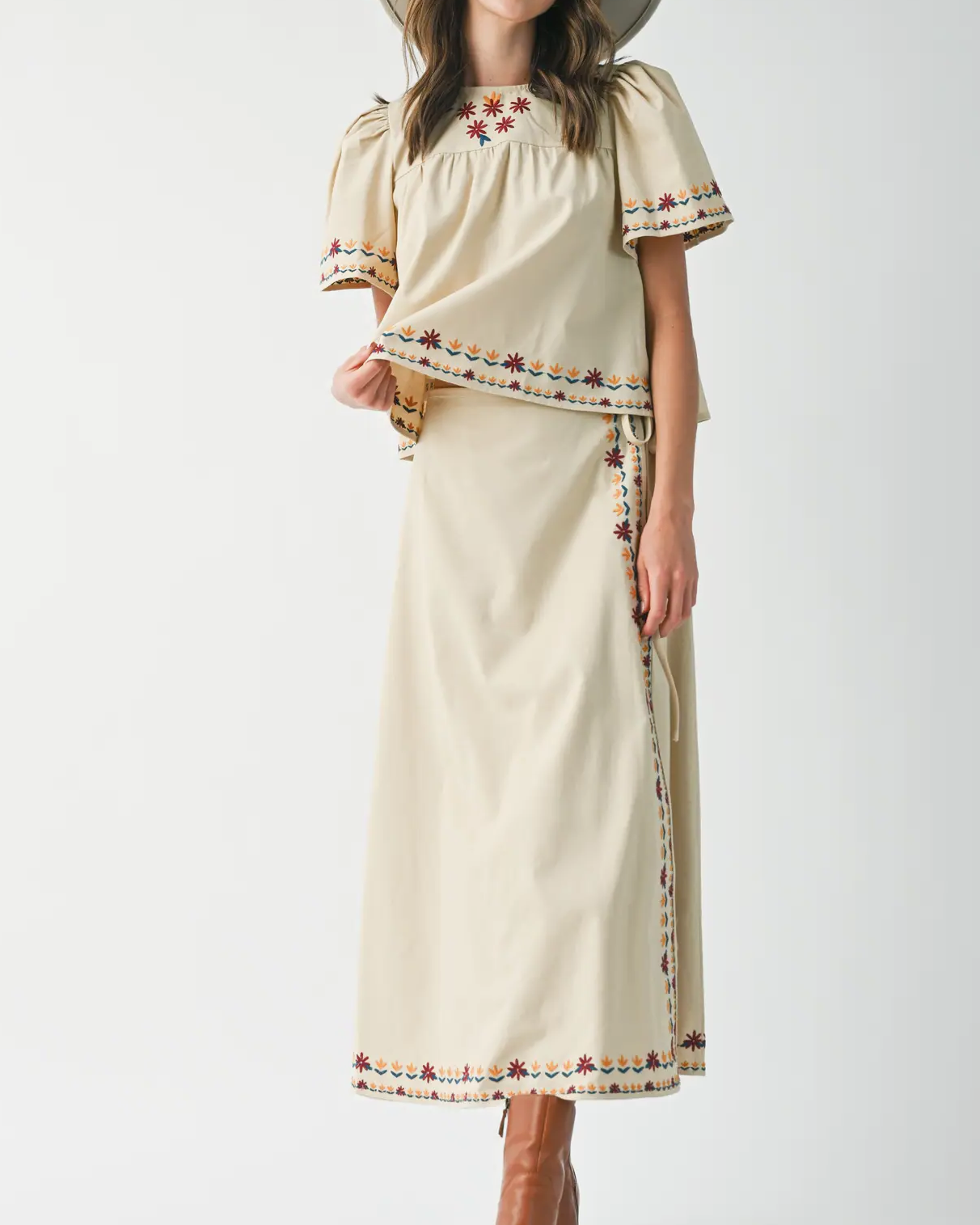 Woman wearing a beige dress with a wide-brimmed hat on a white background