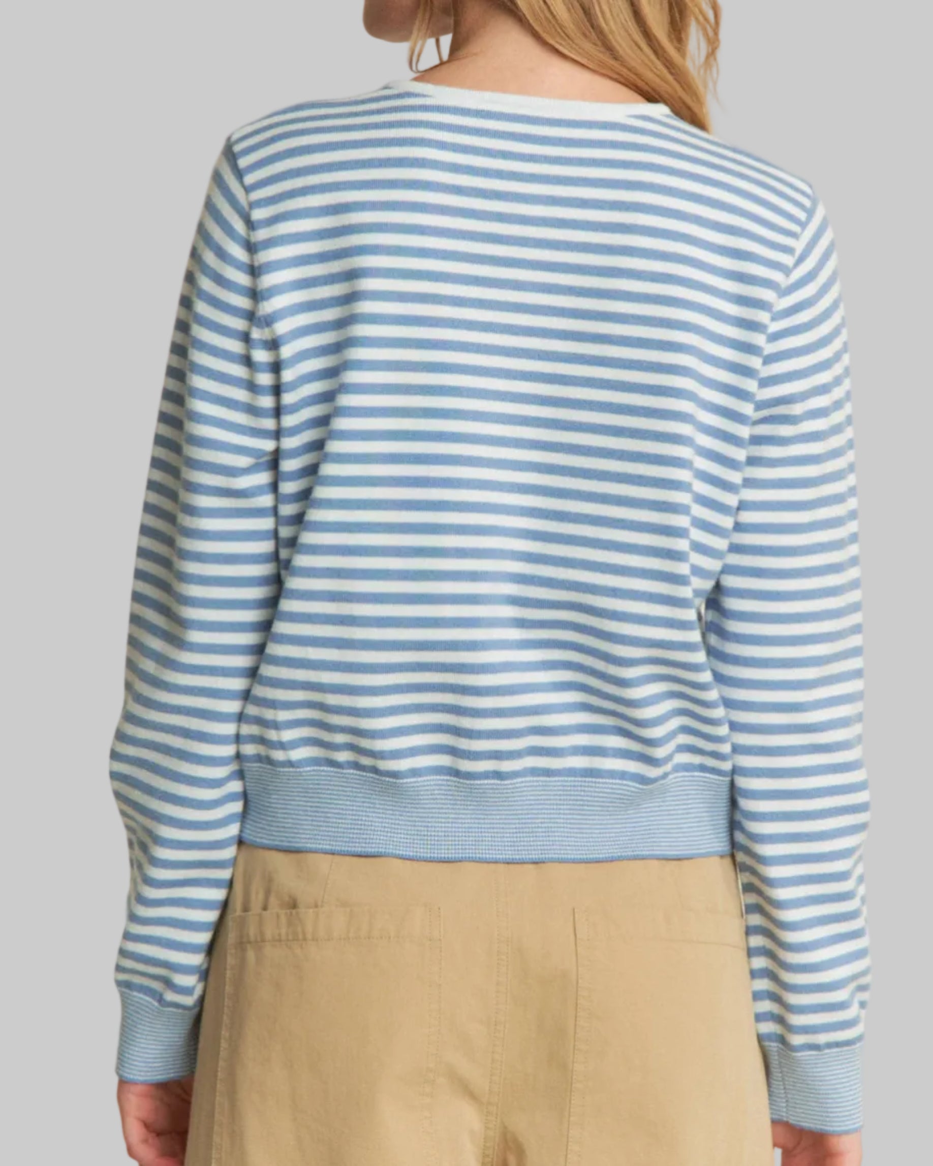 Woman wearing a blue and white striped sweater on a beige background