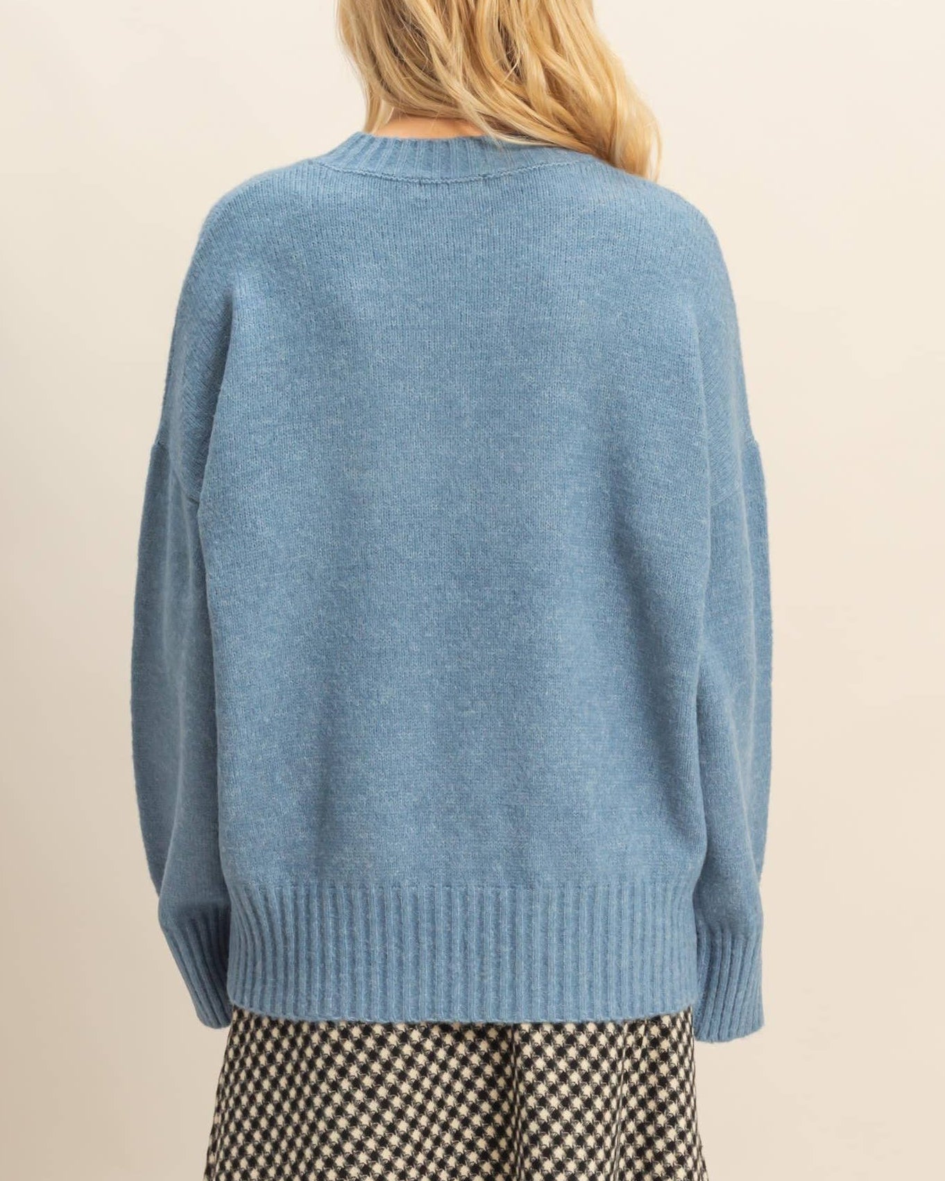 Person wearing a blue sweater with a neutral background