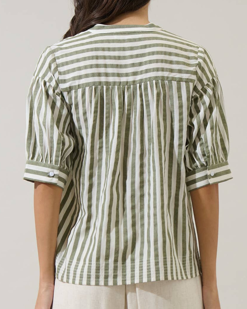 Woman wearing a green and white striped shirt against a plain background