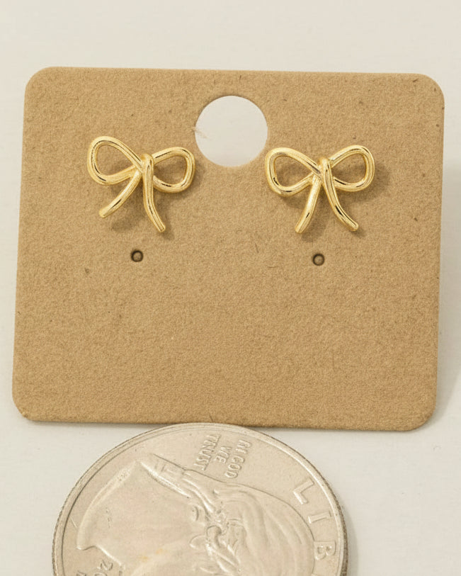 Gold bow-shaped earrings on a cardboard backing with '18K Gold Dipped' text, next to a coin for scale.