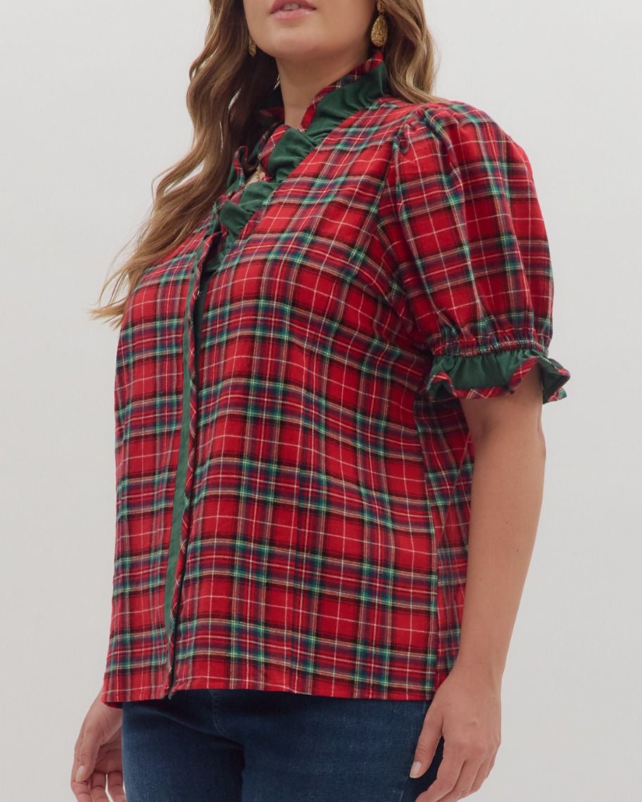 Woman wearing a red plaid shirt with green accents on a white background