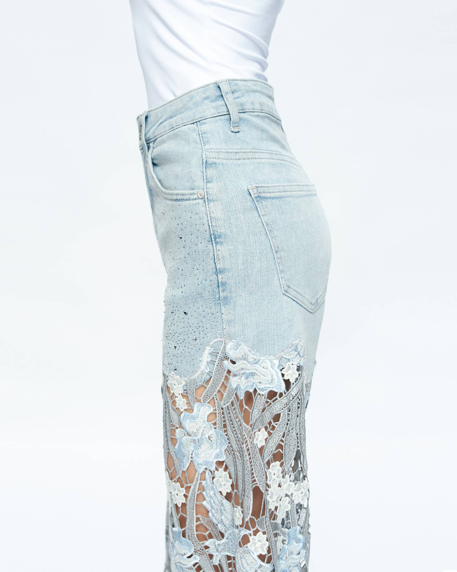 Light blue jeans with floral lace detailing on a white background