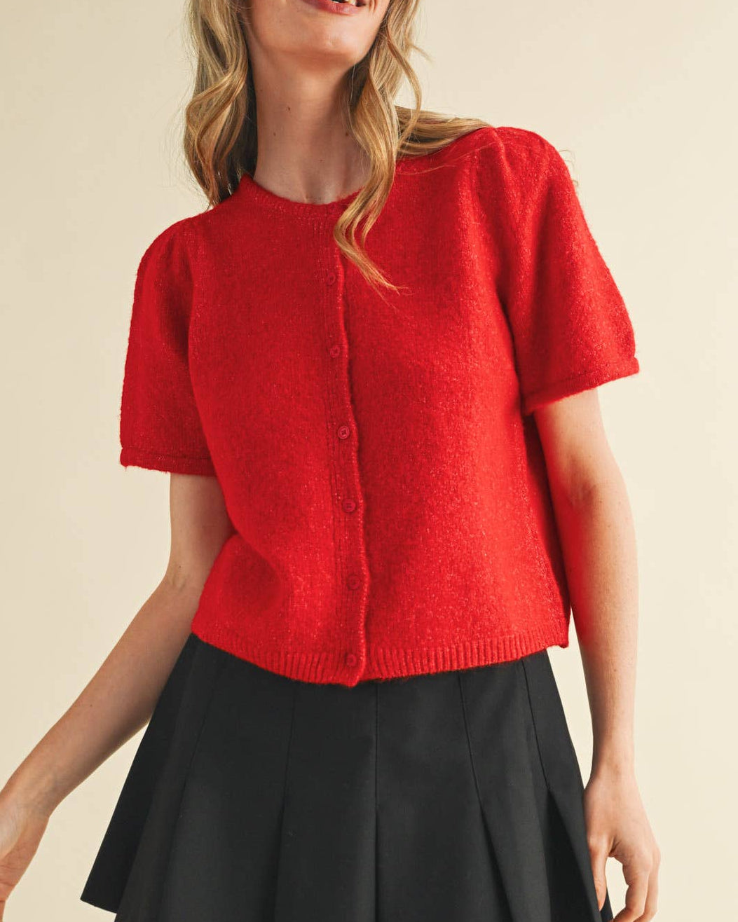 Woman wearing a red sweater and black skirt on a beige background