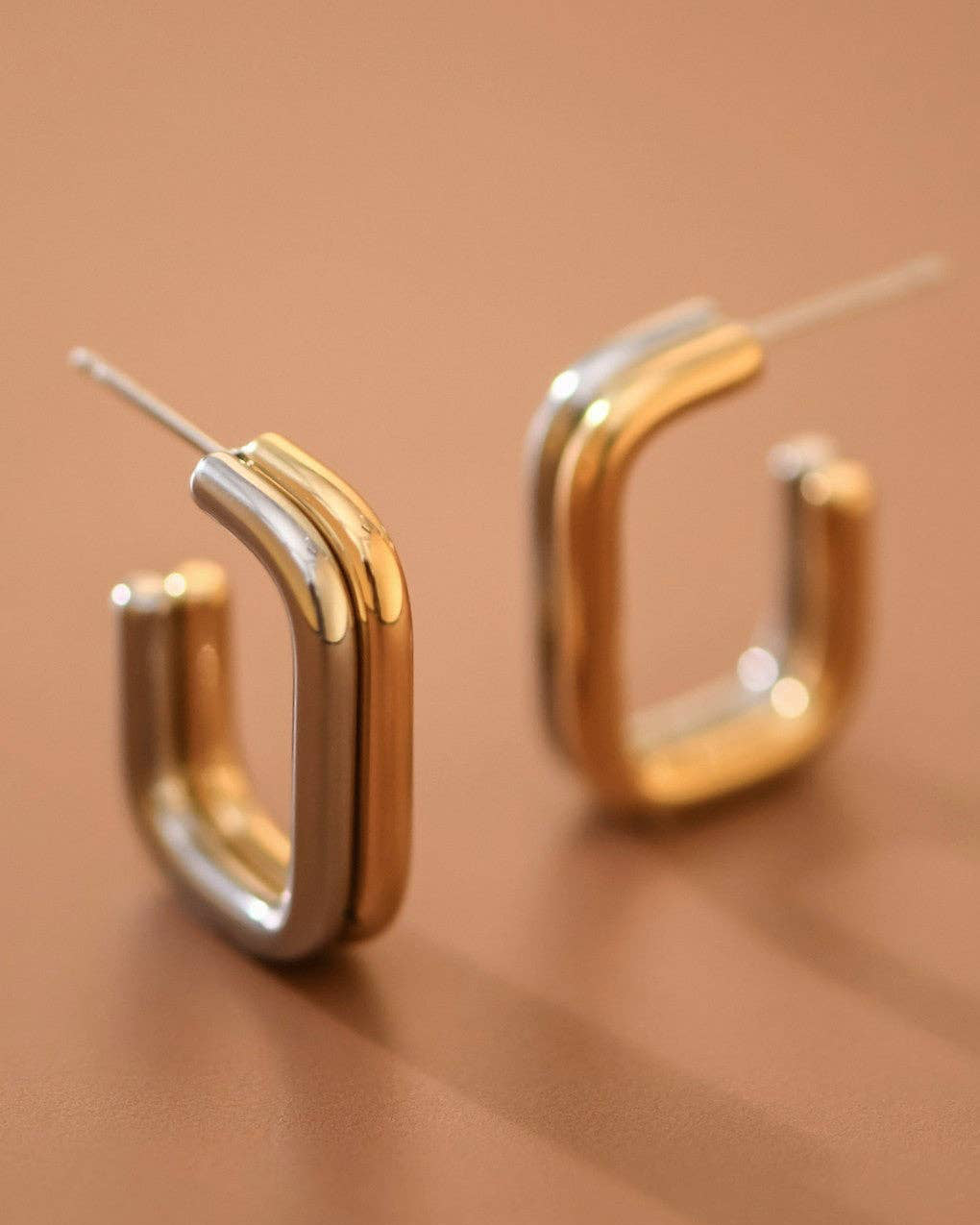 Gold hoop earrings on a brown background
