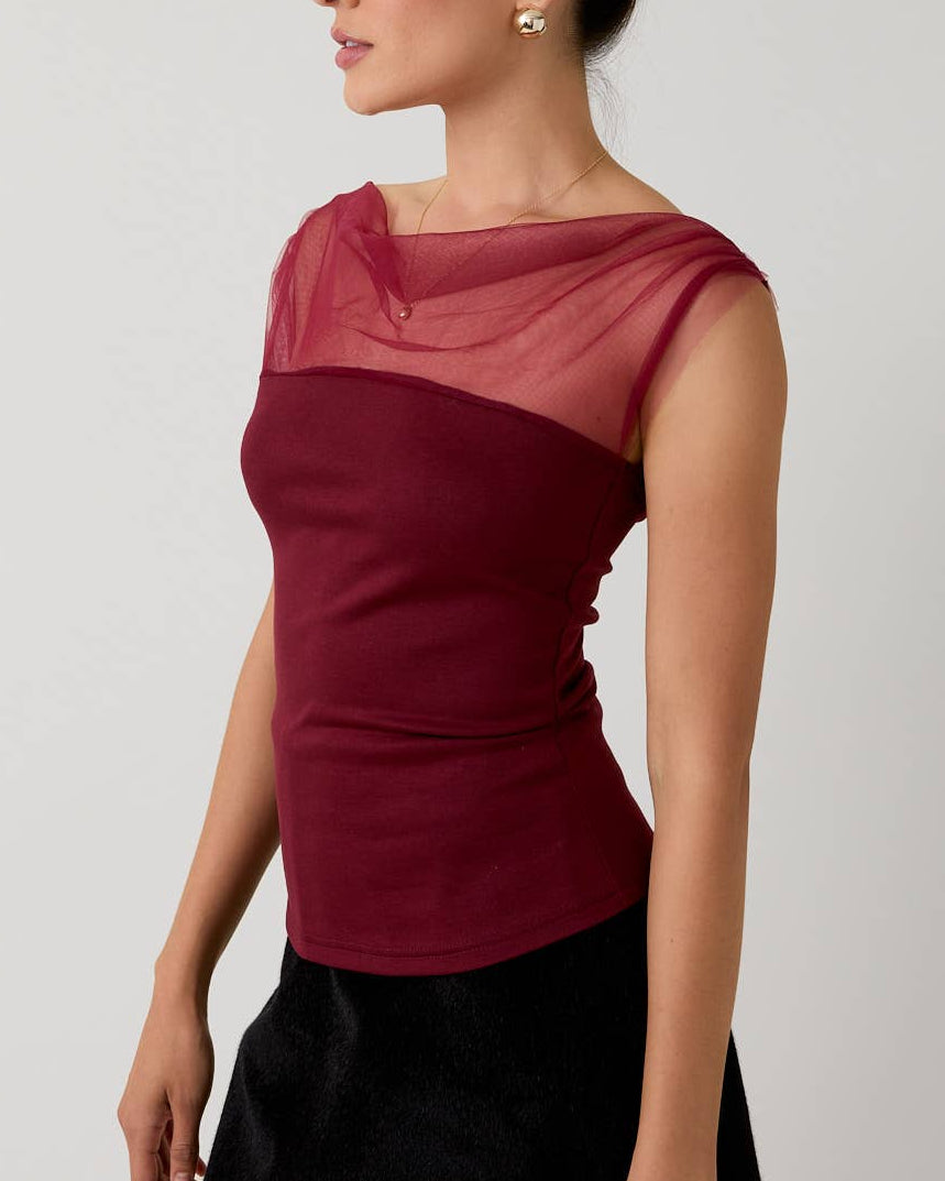 Woman wearing a two-tone top with a plain background