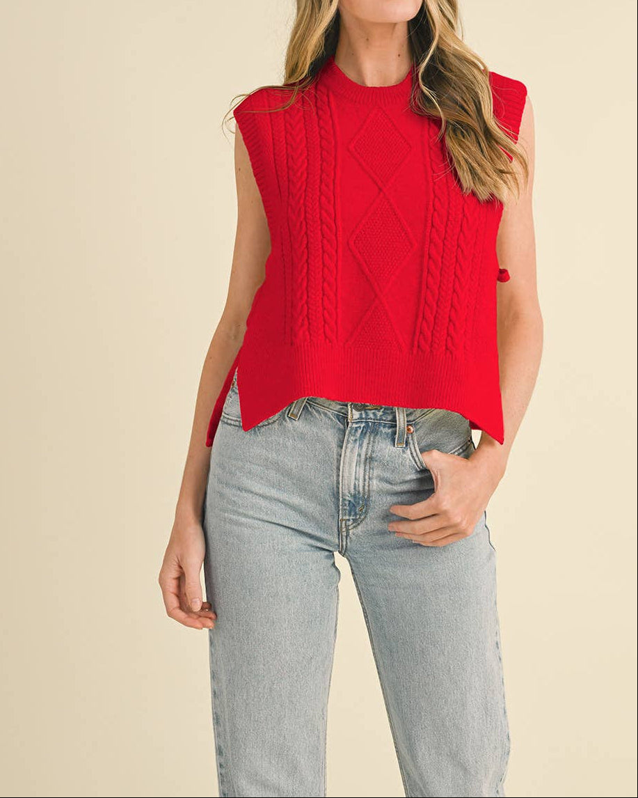 Woman wearing a red sleeveless knitted top and light blue jeans on a beige background