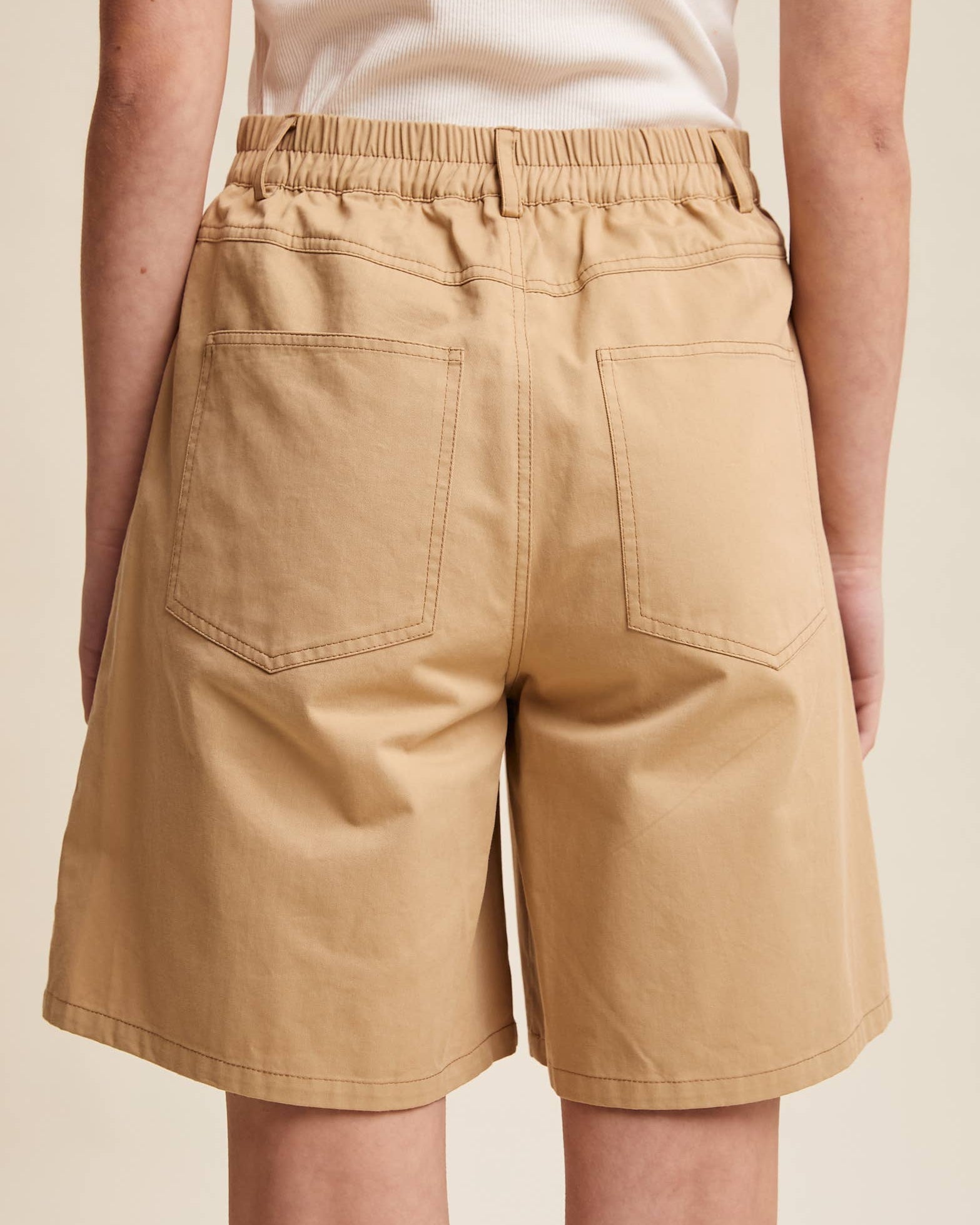 Beige shorts worn by a person on a beige background