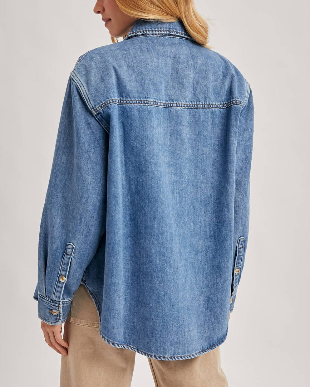 Woman wearing a blue denim shirt against a plain background