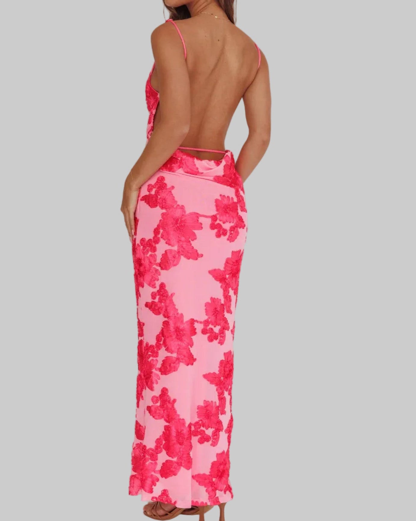 Woman wearing a pink floral dress with an open back on a white background