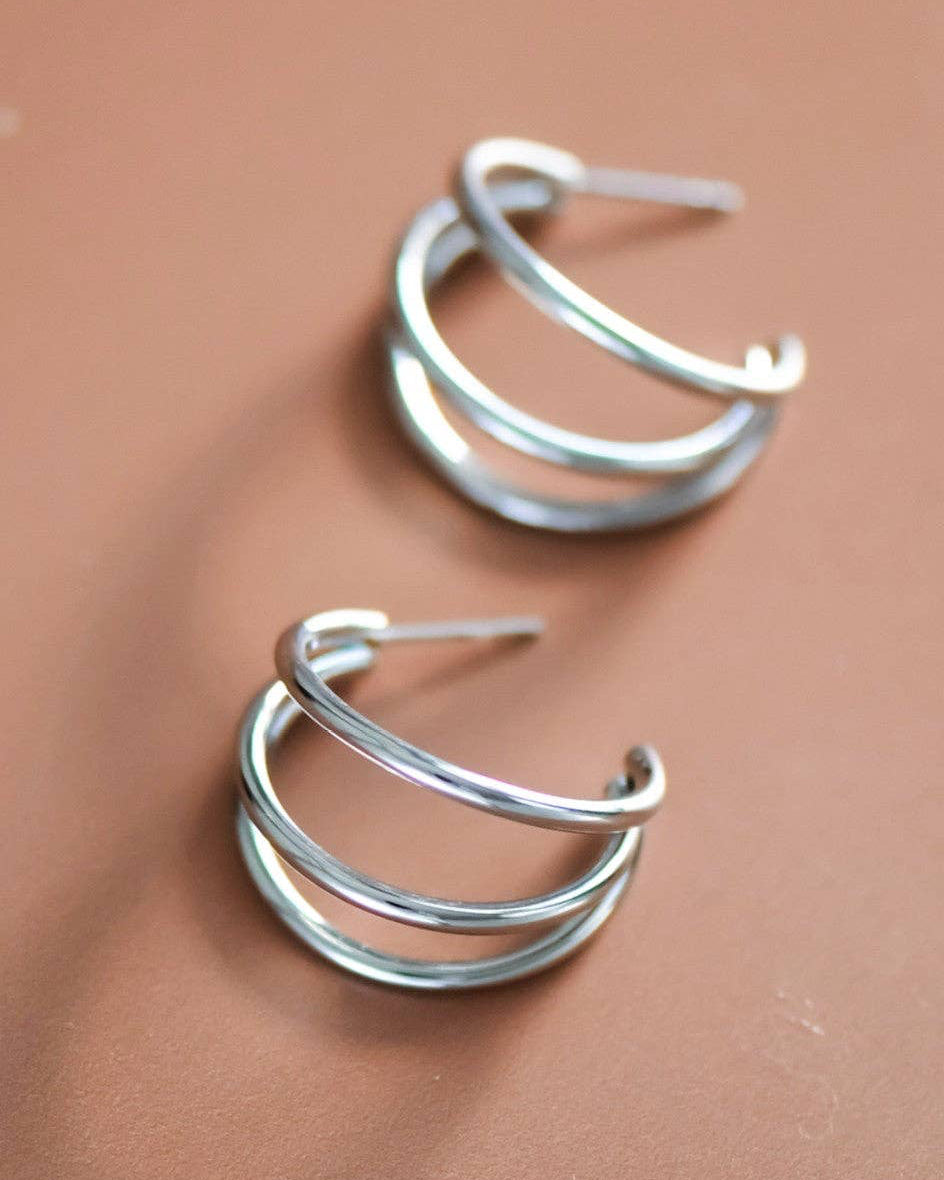 Pair of silver hoop earrings on a brown background