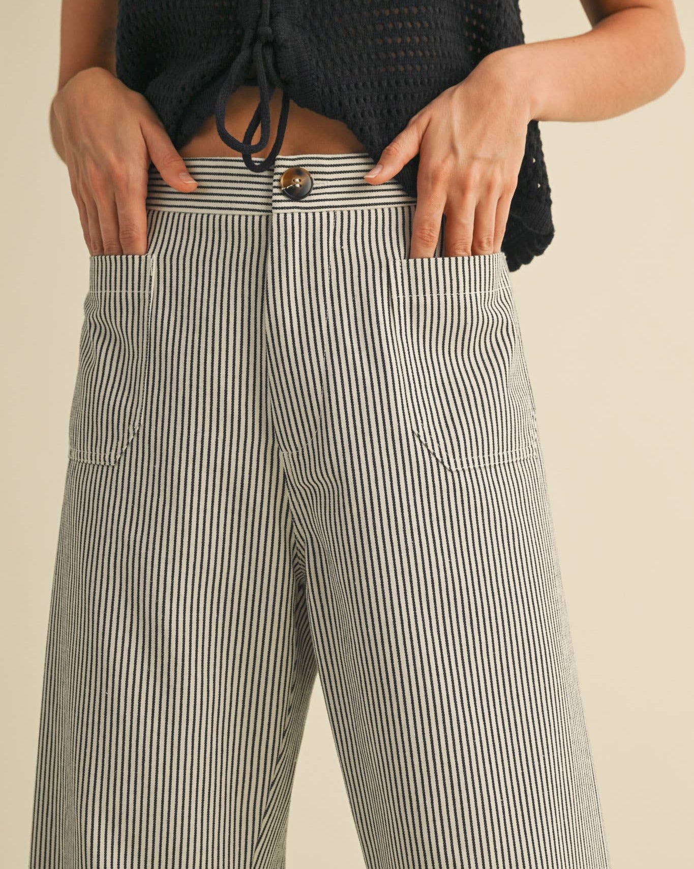 Wide leg cropped pants with black pinstripe on white. Close up view