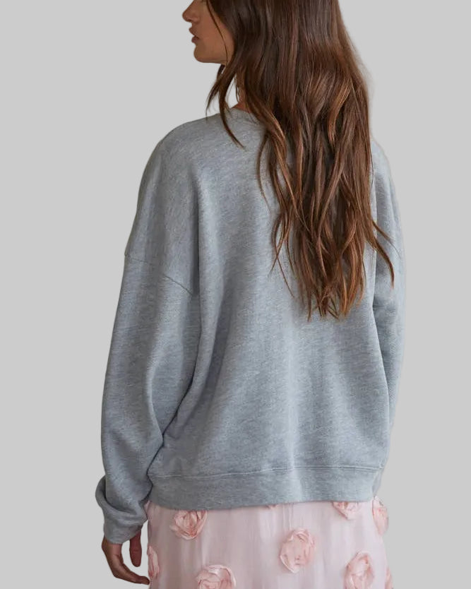 Woman wearing a gray sweater with a plain background