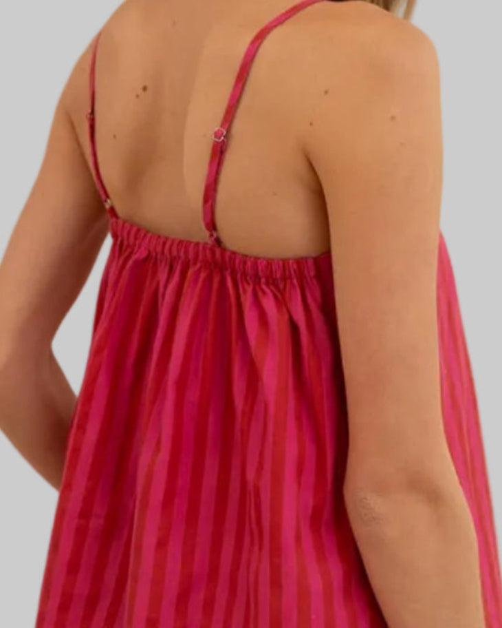 Woman wearing a red checkered dress in a room with white walls and a window.