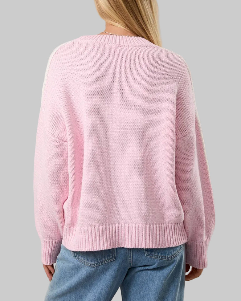 Person wearing a pink sweater and blue jeans on a plain background