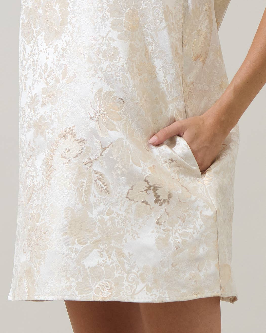 Close-up of a person wearing a white floral dress with a neutral background