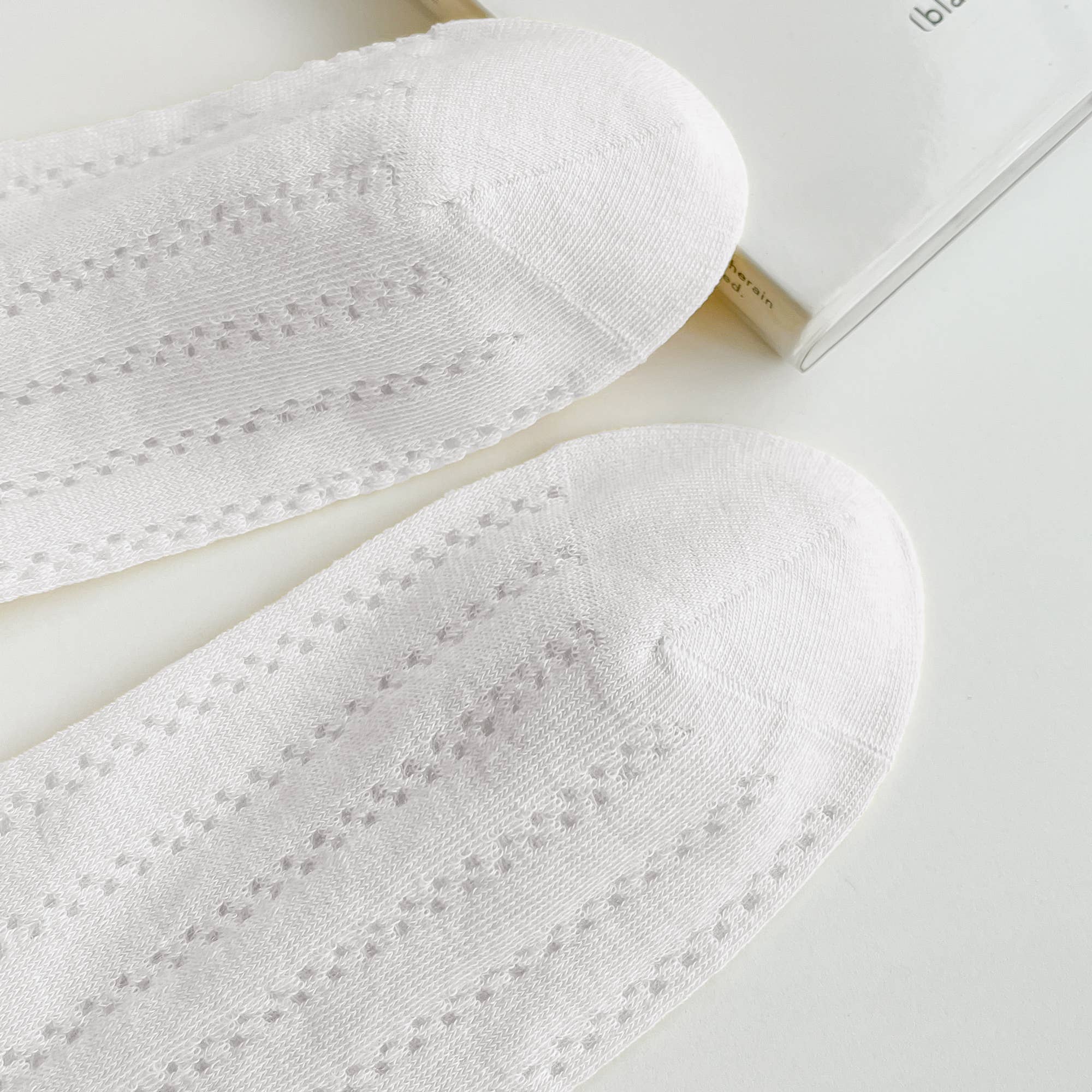 White socks with subtle pattern on a light gray background