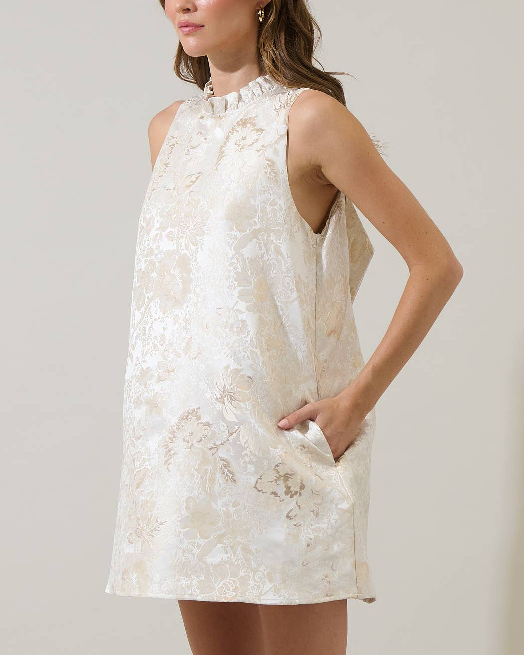 Woman wearing a white jacquard dress against a plain background