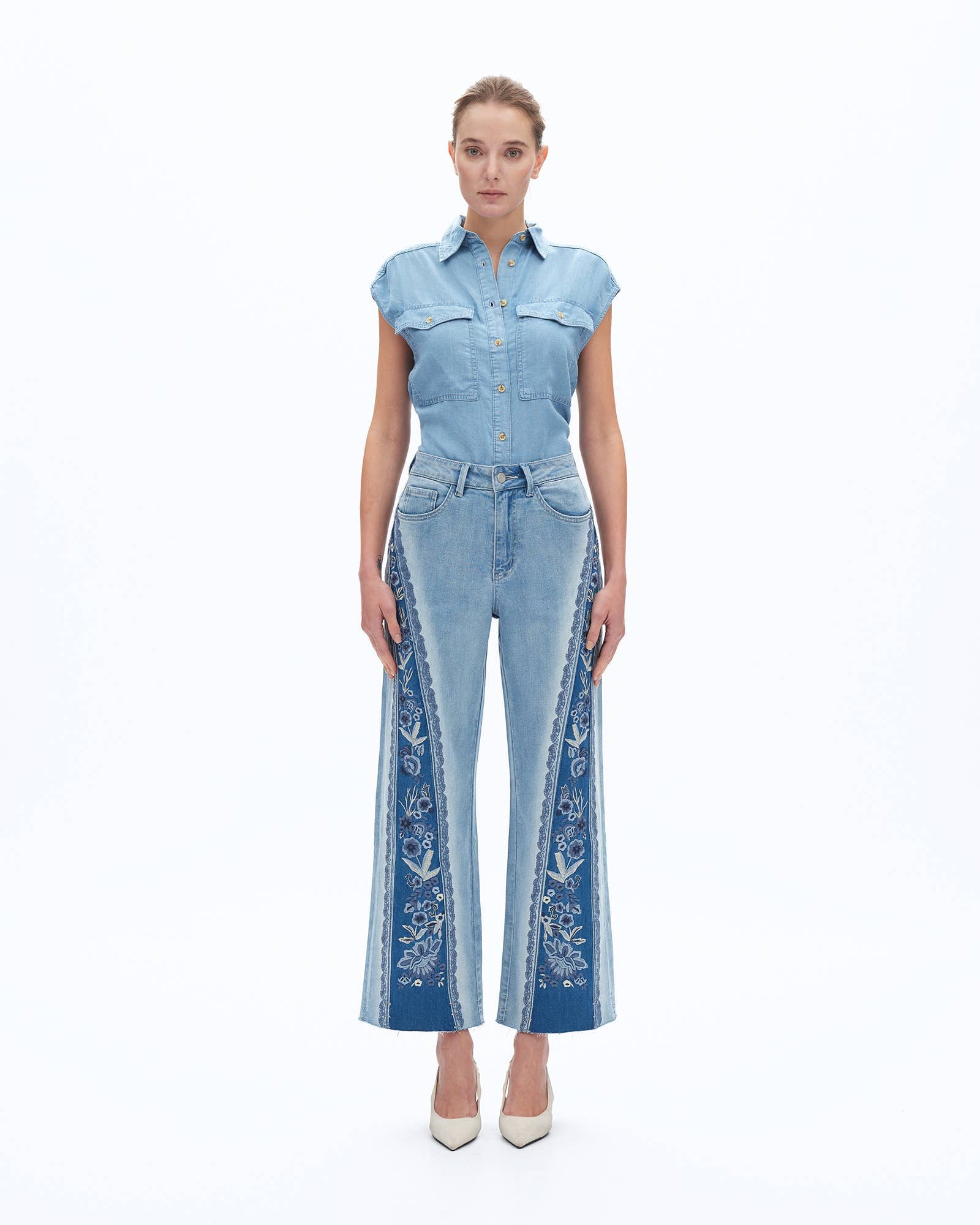Woman wearing a denim outfit with embroidered details on a white background