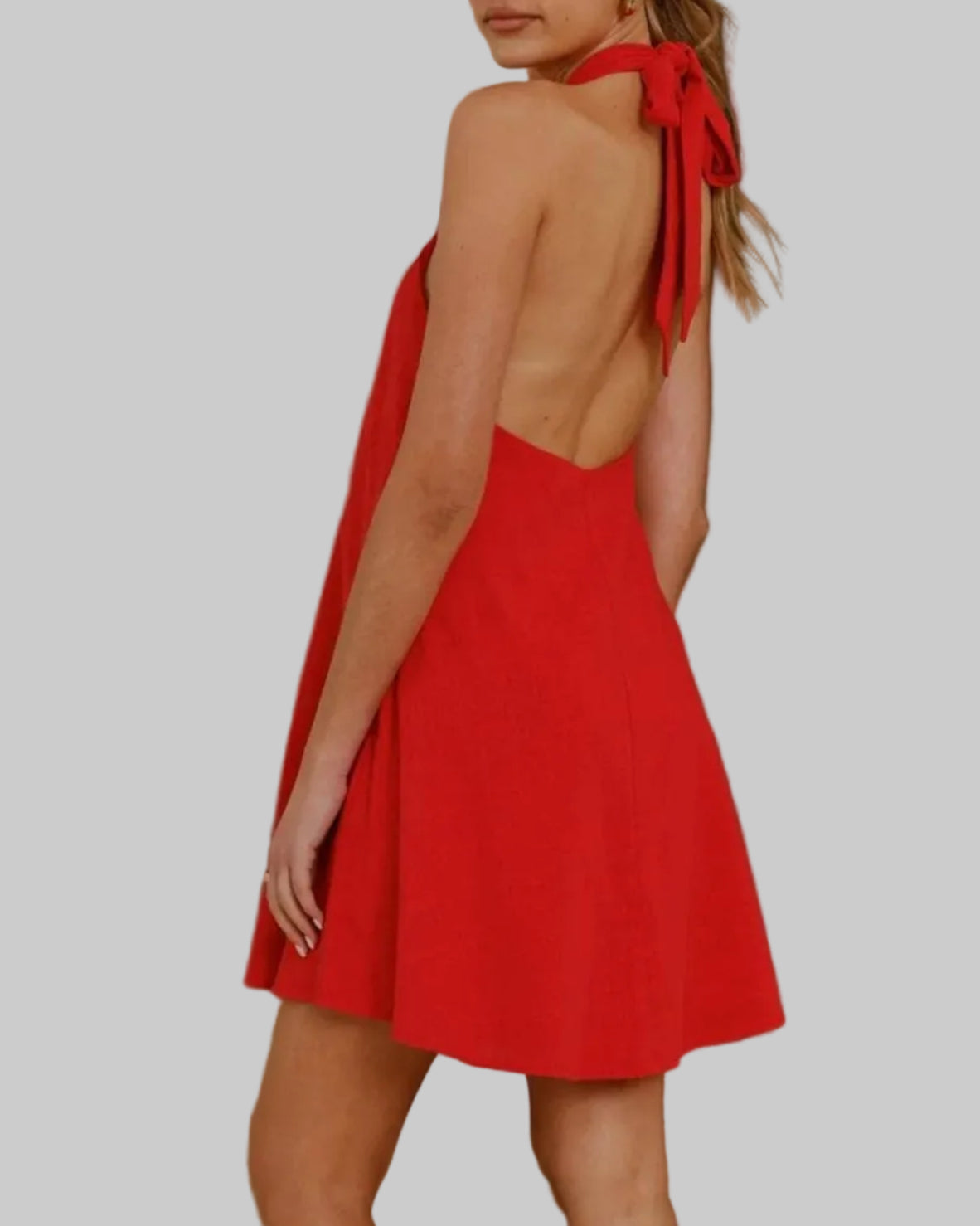 Woman wearing a red dress with a backless design in an indoor setting.