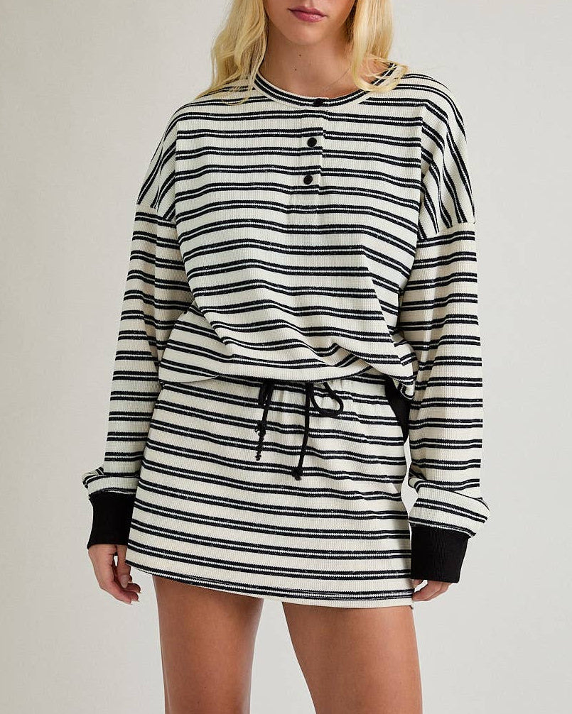 Woman wearing a black and white striped skort set on a plain background