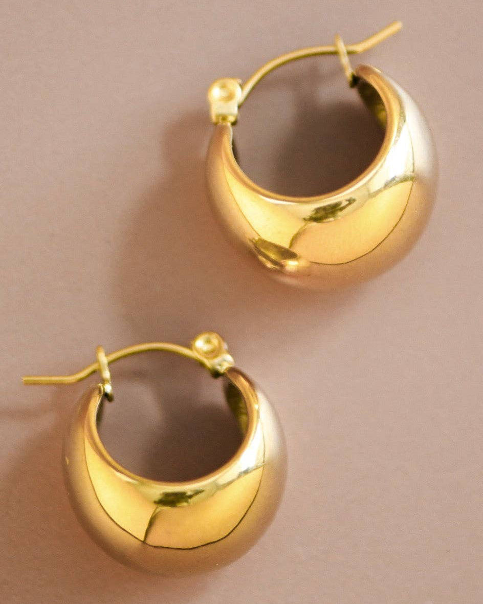 Gold hoop earrings on a beige background