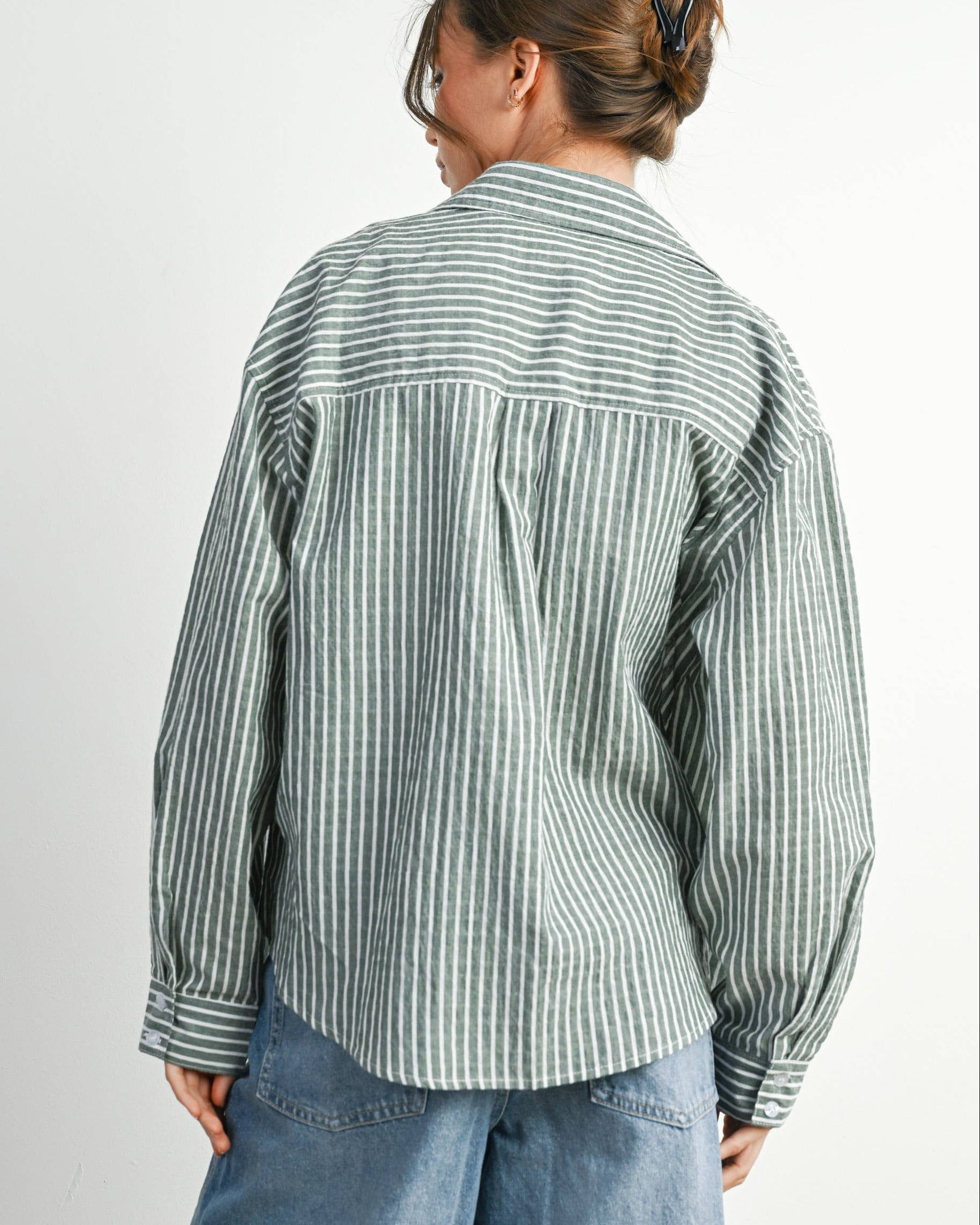 Person wearing a striped shirt and blue jeans on a plain background