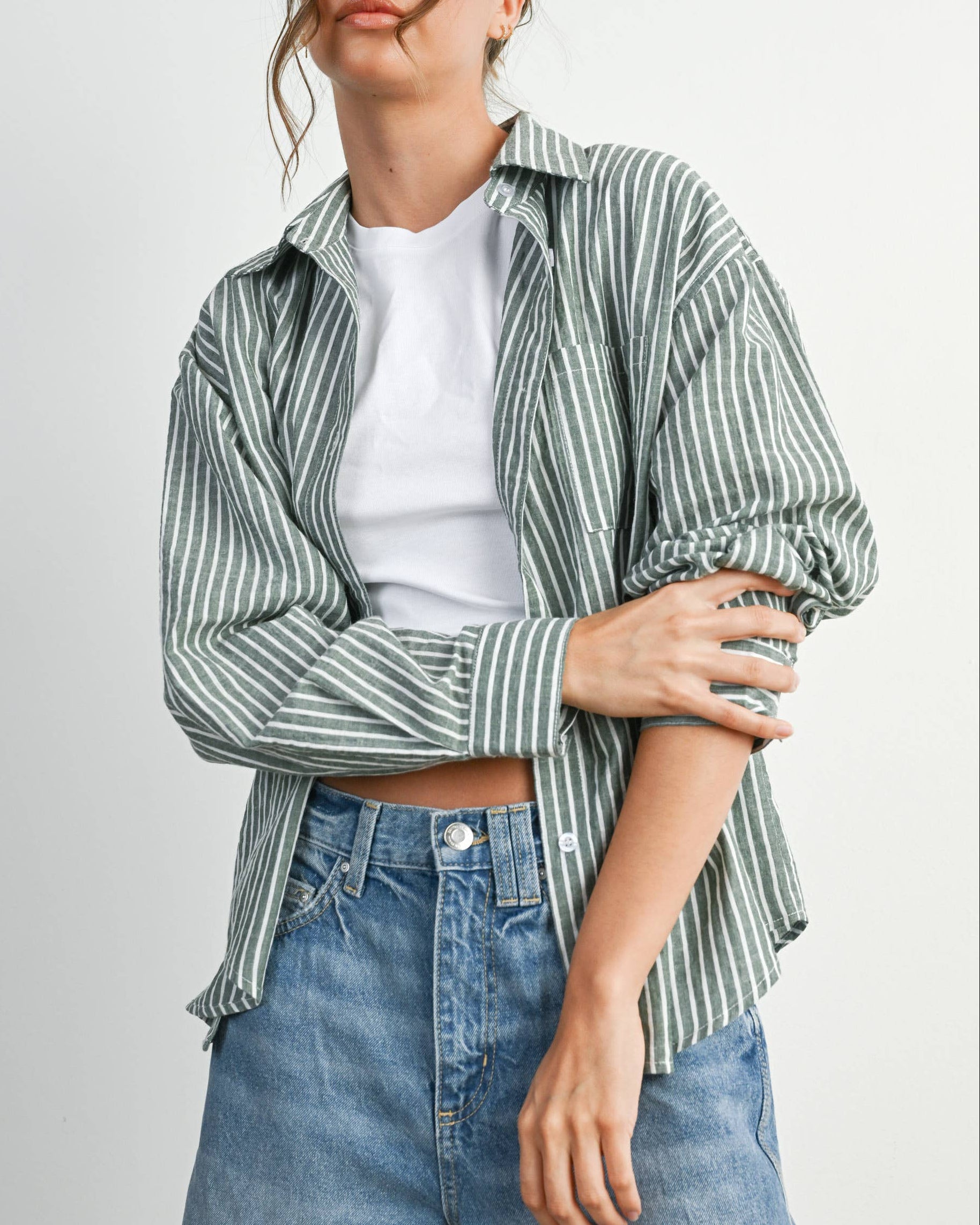 Woman wearing a striped shirt and jeans on a plain background