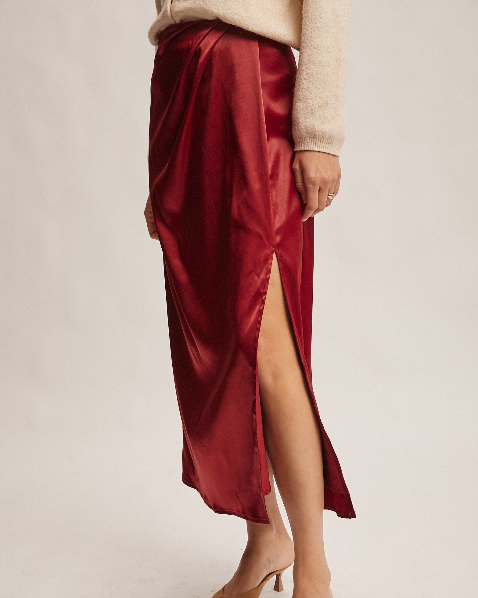 Red satin skirt with a high slit worn by a person on a plain background