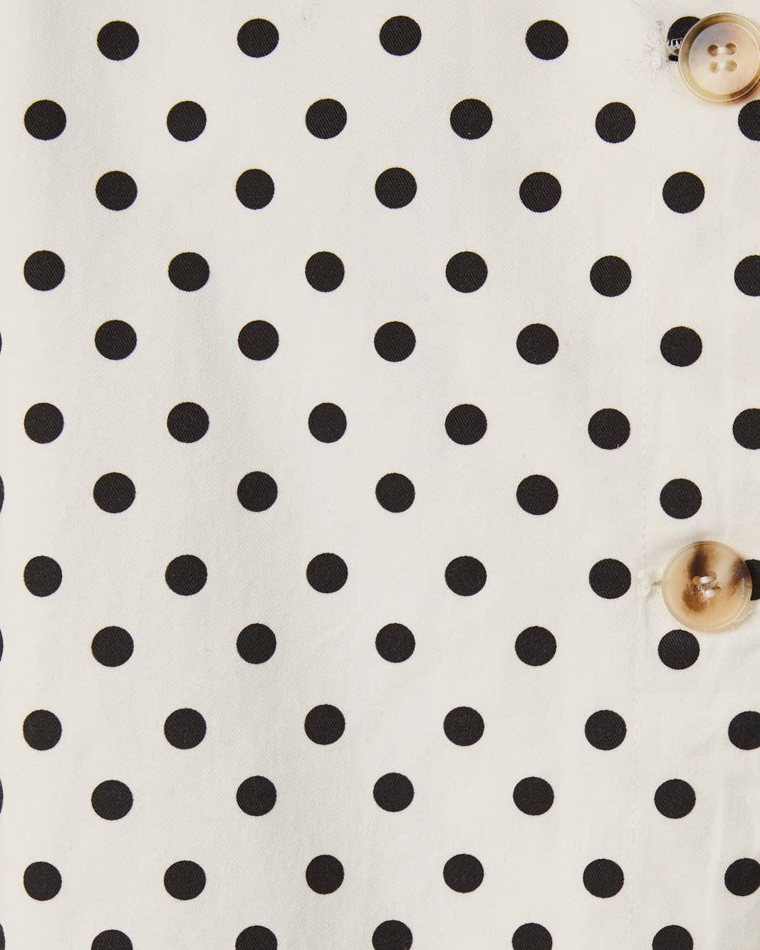 White fabric with black polka dots and gold buttons on the side.