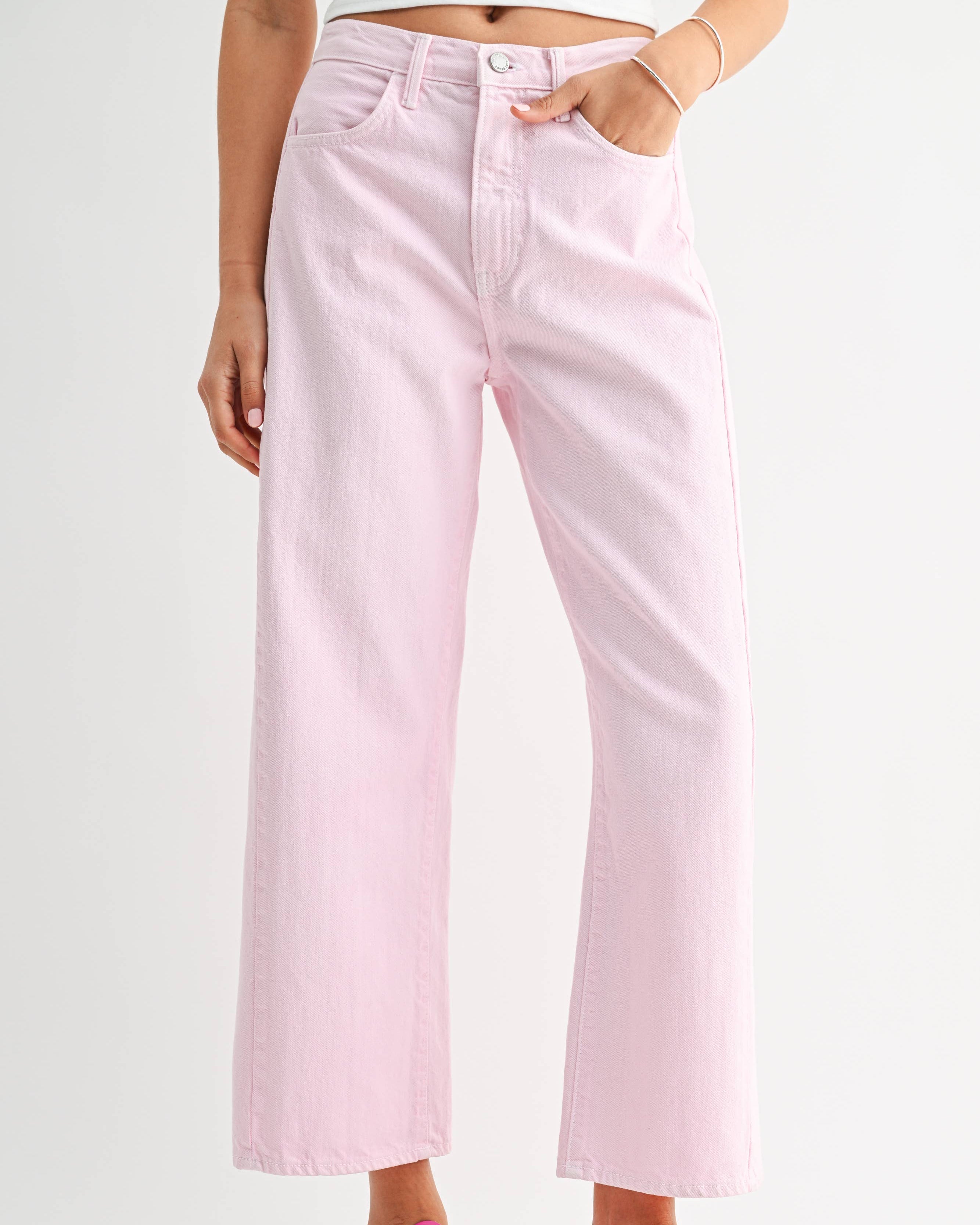 Person wearing light pink jeans and pink sneakers on a white background