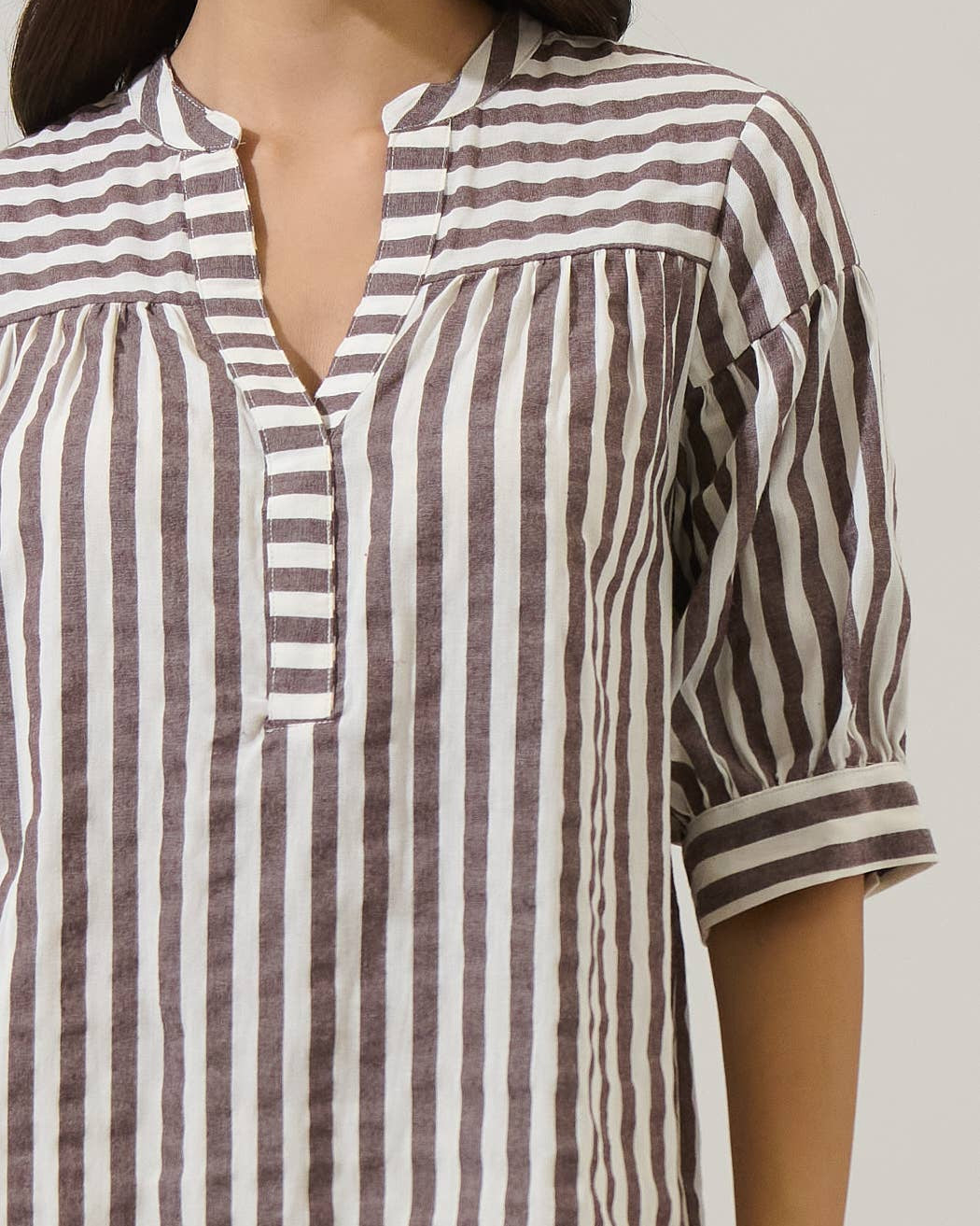 Striped shirt with a V-neck and 3/4 sleeves on a plain background