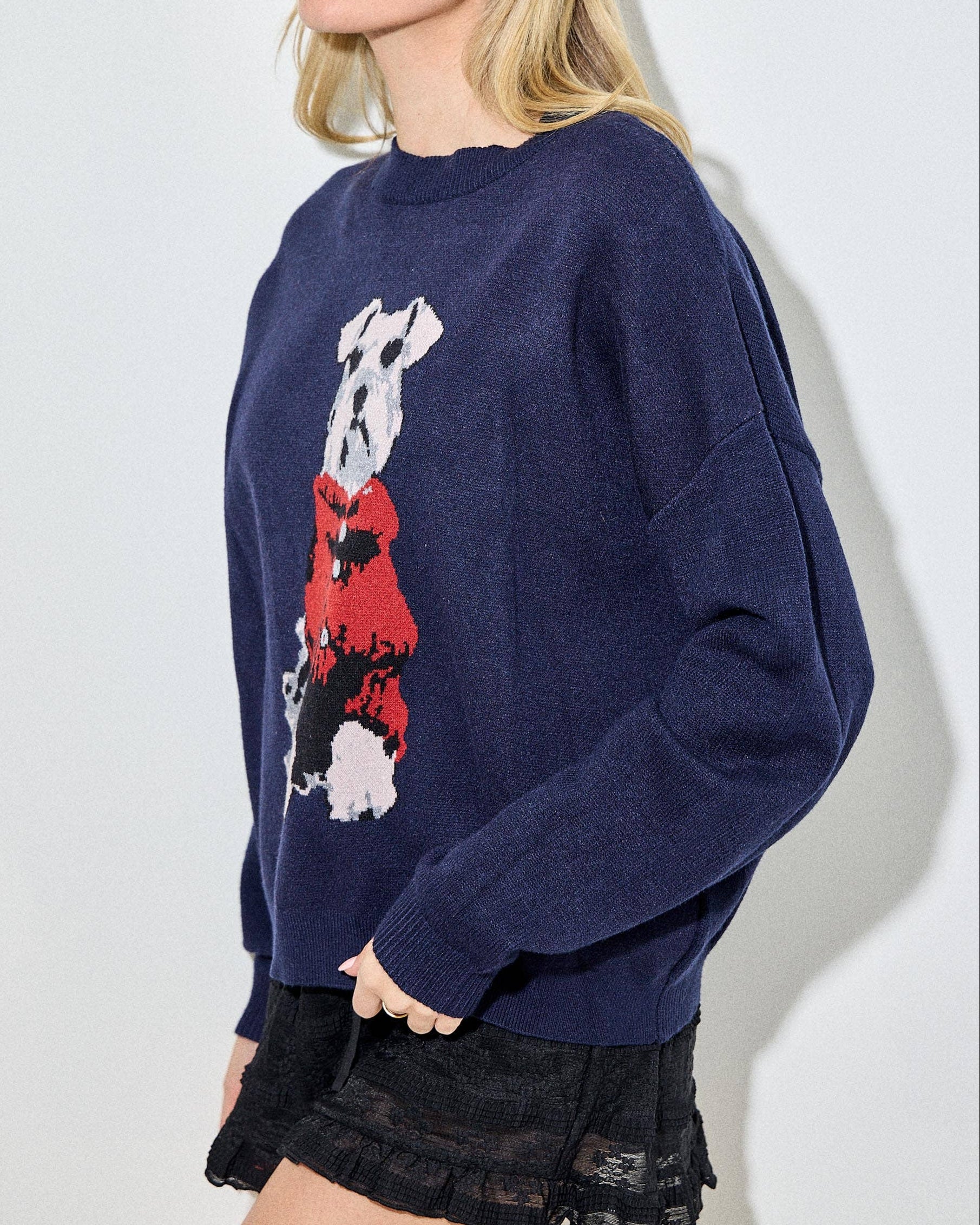 Woman wearing a navy blue sweater with a graphic design of a dog and a red dress on a white background