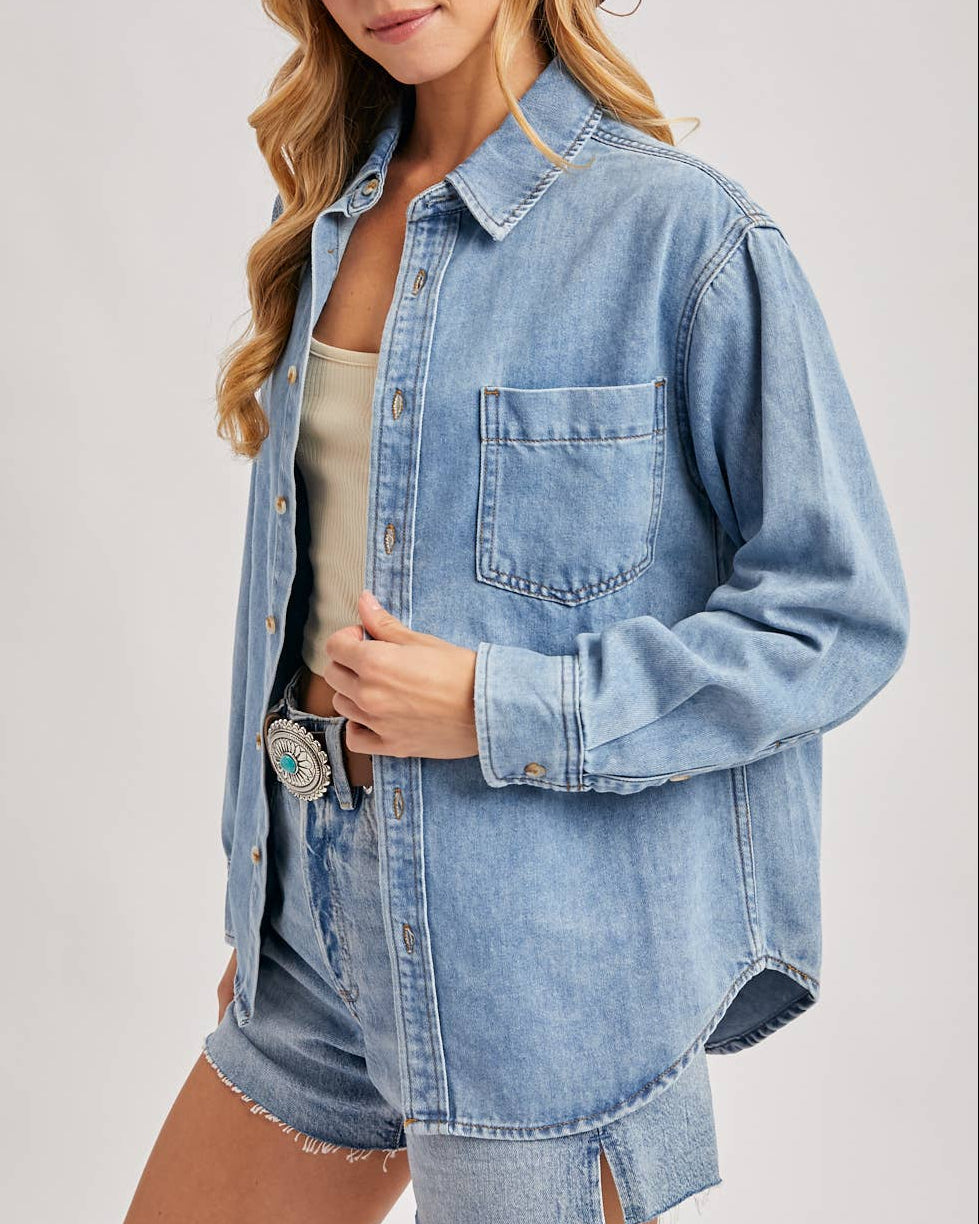 Woman wearing a denim jacket and brown hat on a plain background