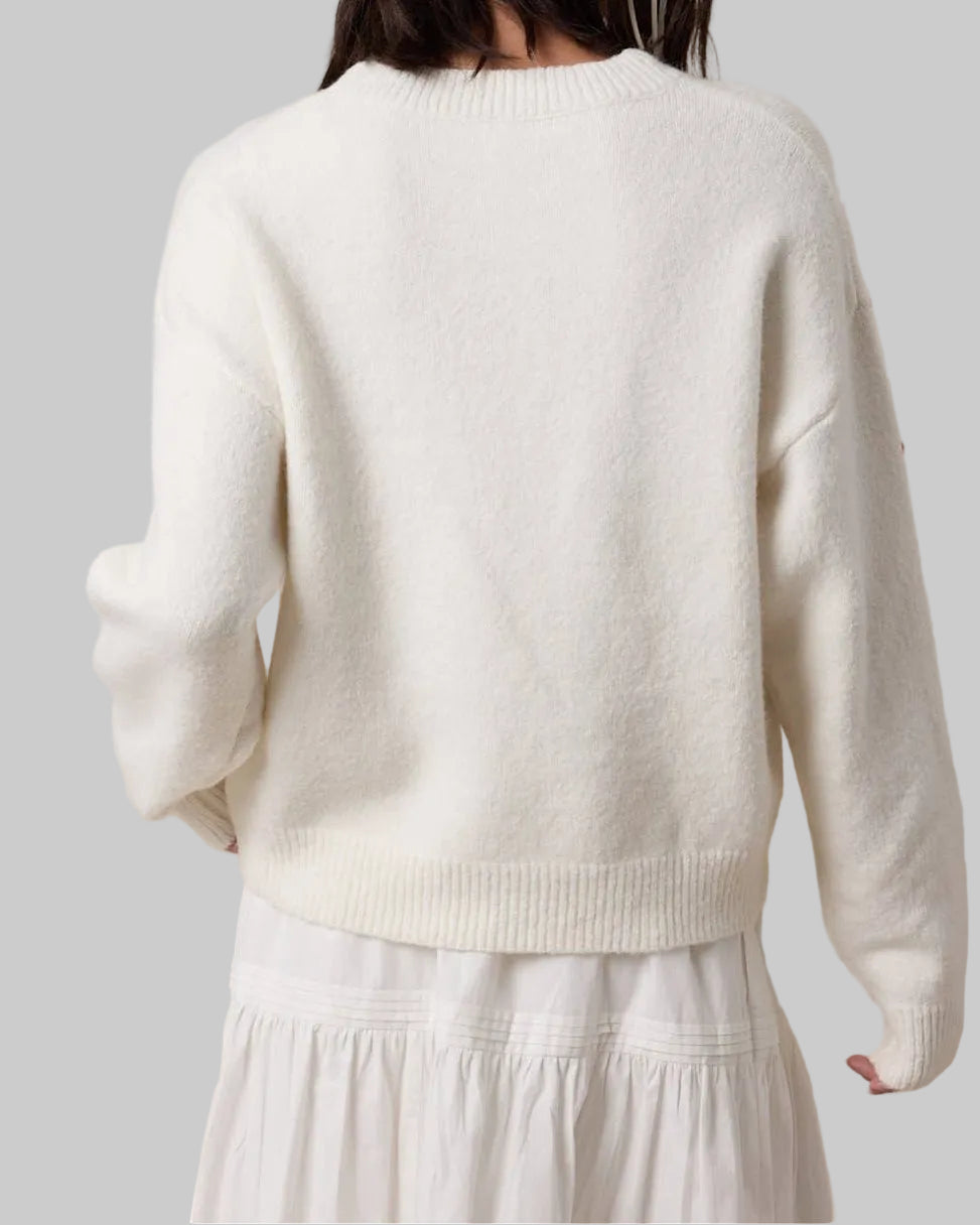 Woman wearing a white sweater and skirt against a beige background