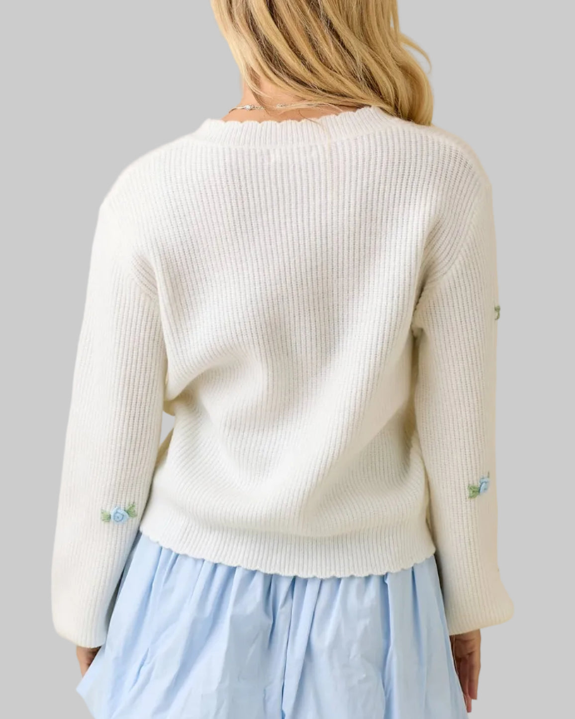 Woman wearing a white sweater and light blue skirt on a beige background