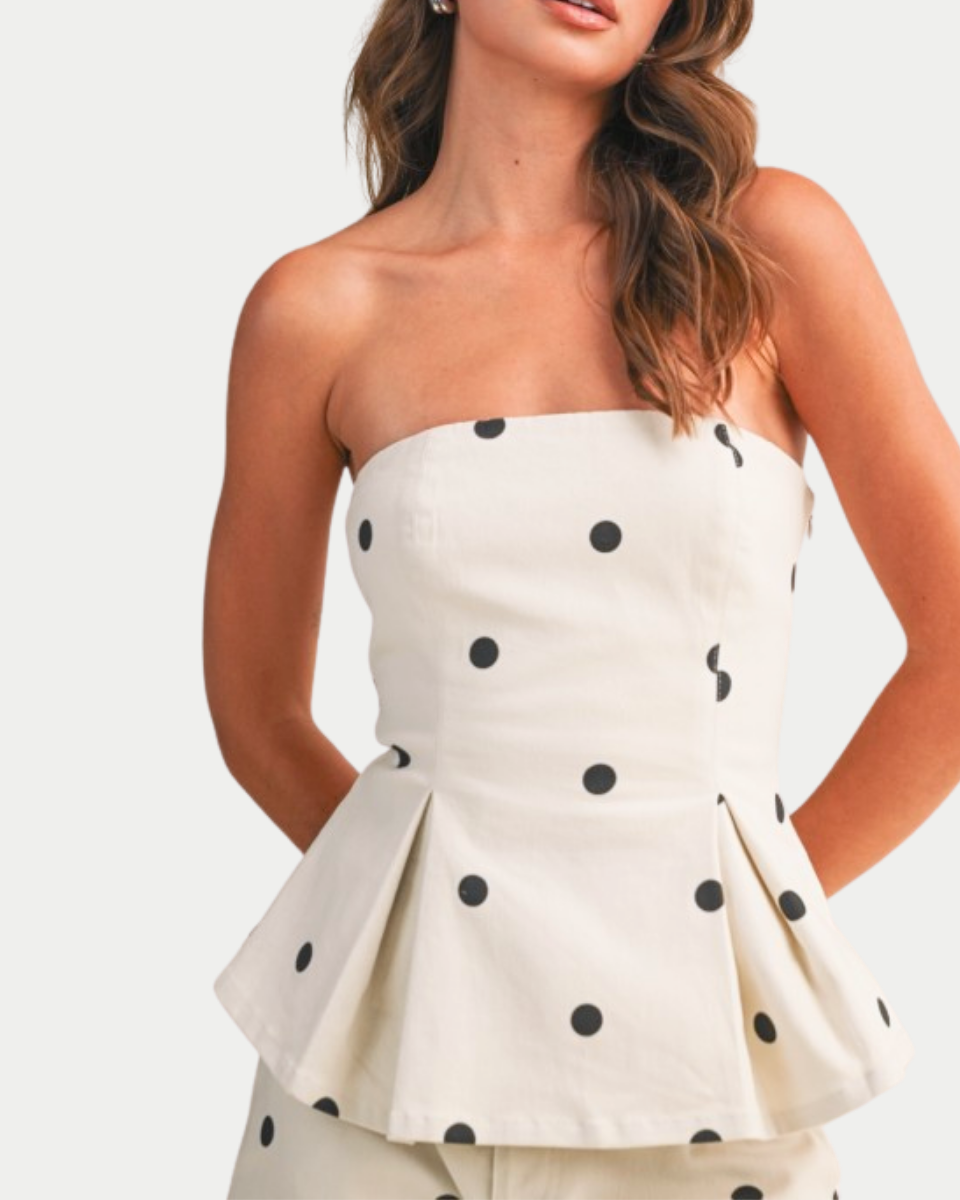 White strapless dress with black polka dots worn by a model on a white background