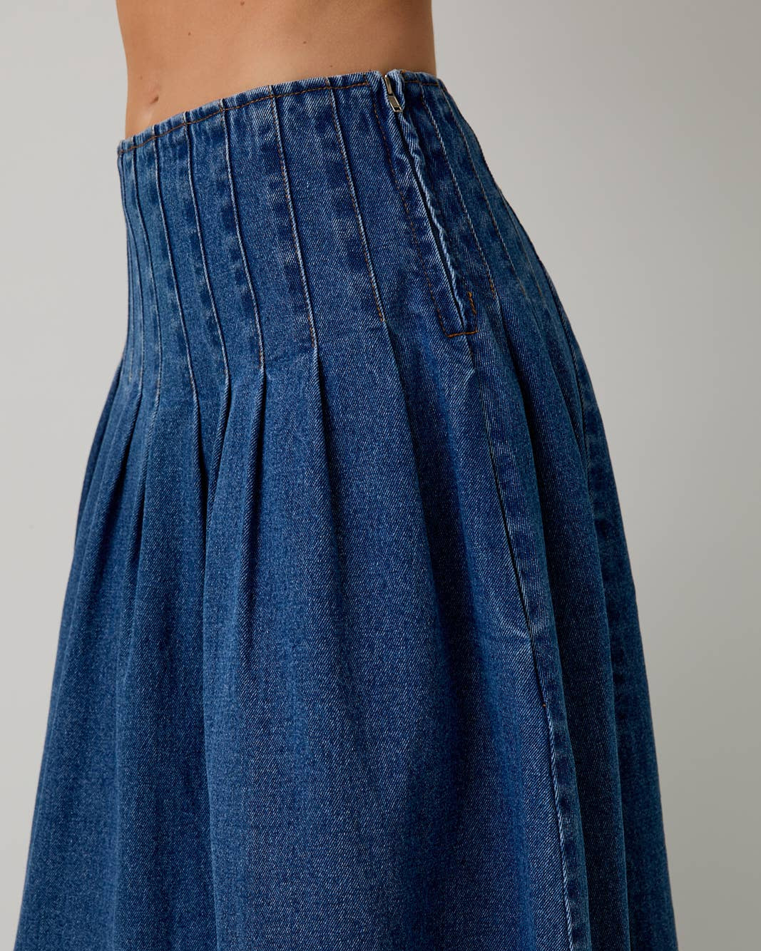 Blue denim skirt with pleated waistband on a neutral background