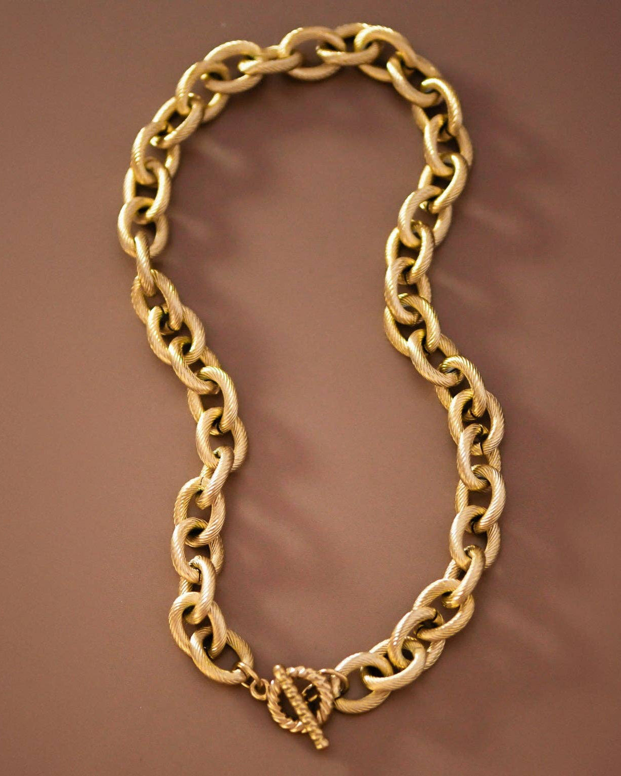 Gold chain necklace on a brown background