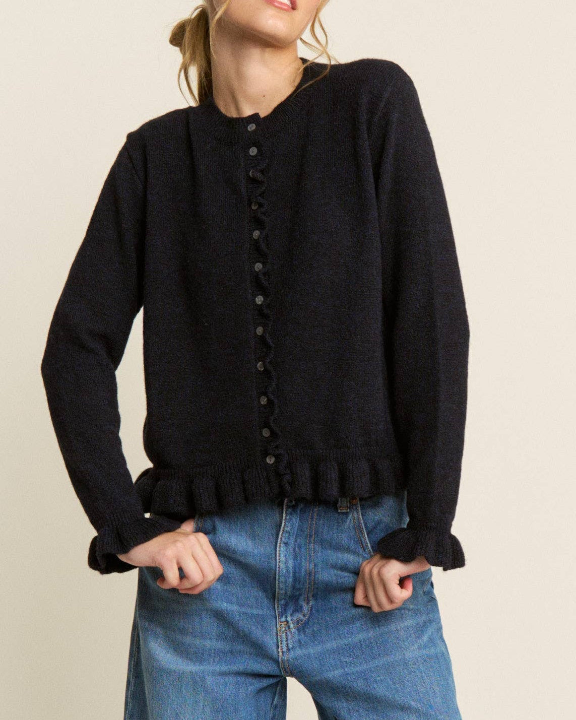 Woman wearing a black cardigan and blue jeans on a white background