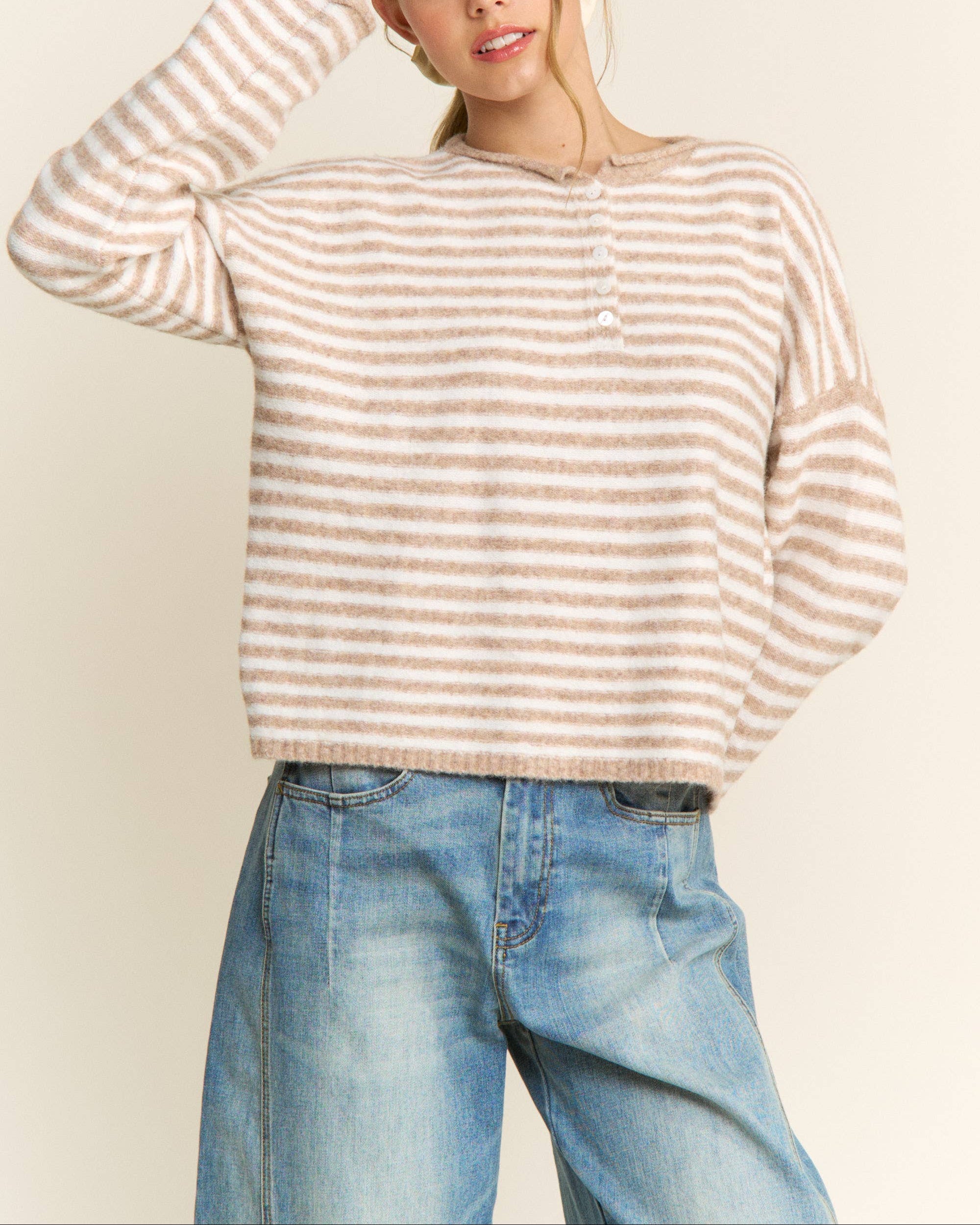 Woman wearing a striped sweater and jeans against a plain background