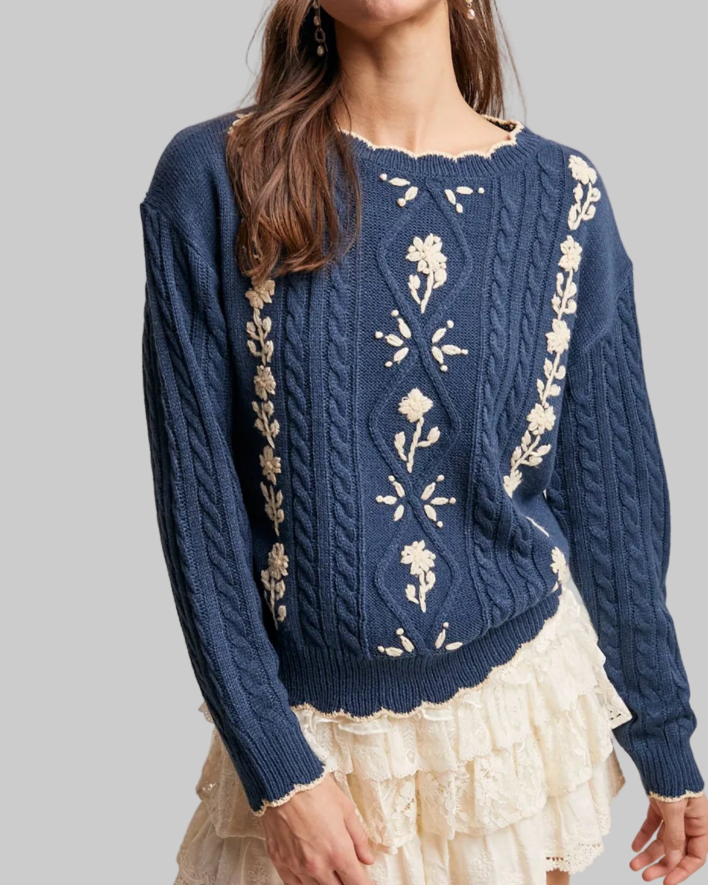 Woman wearing a blue sweater with floral patterns on a beige background