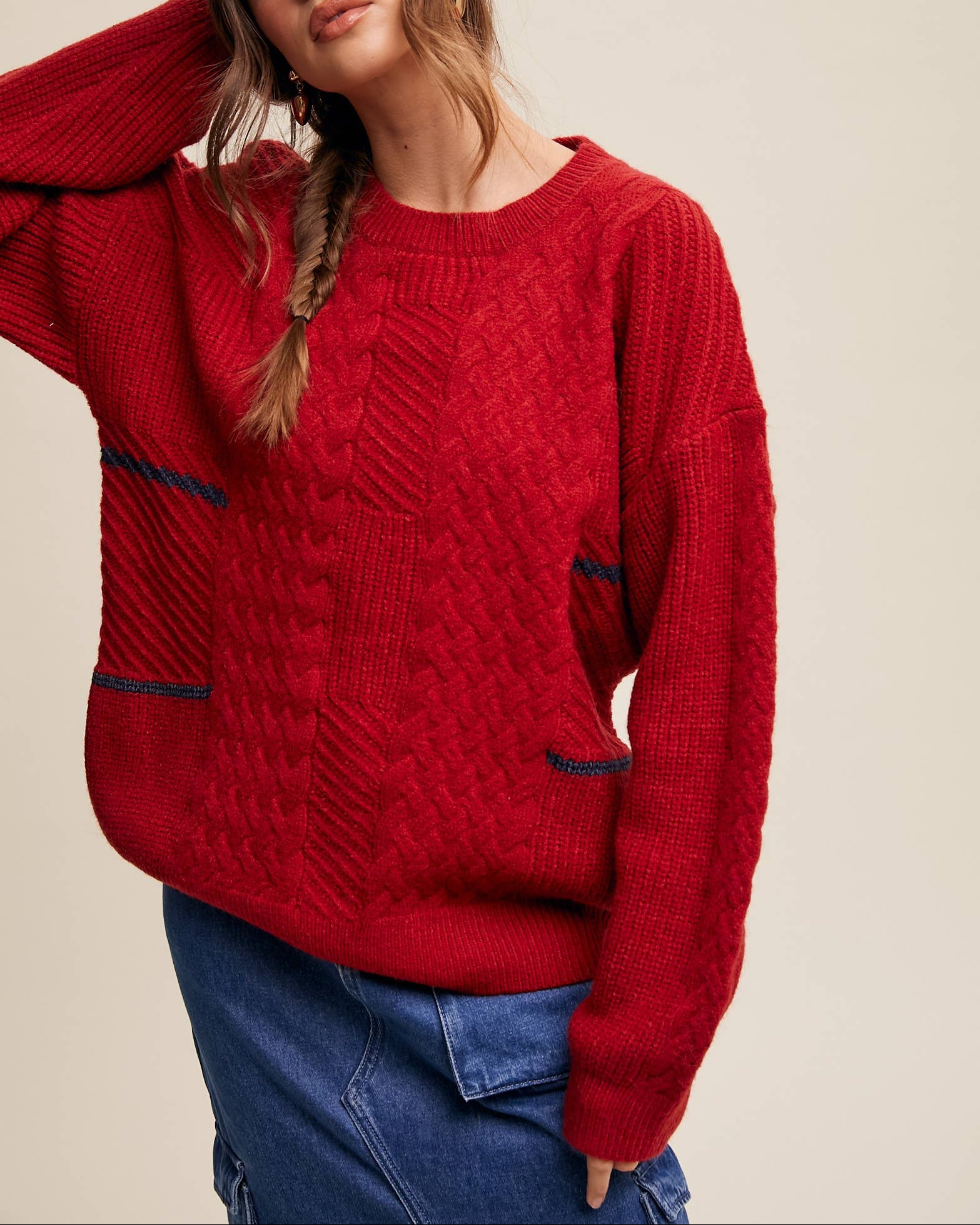 Woman wearing a red sweater and blue cap against a beige background