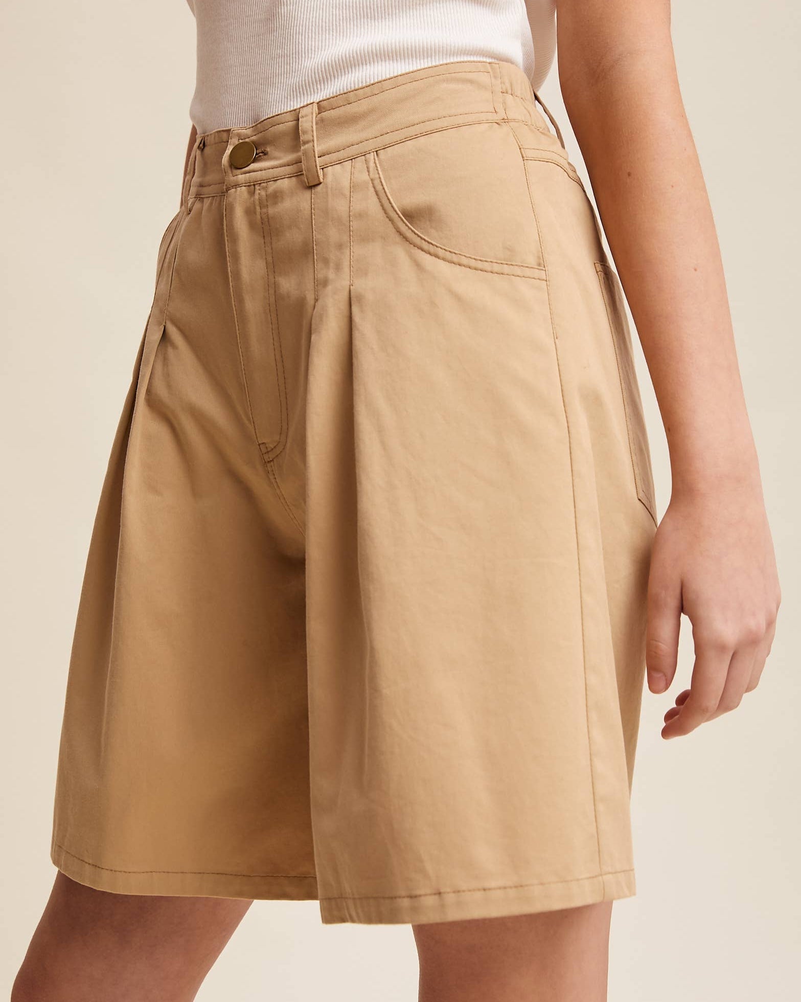 Beige shorts worn by a person on a beige background