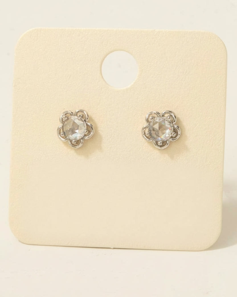 Pair of silver stud earrings on a beige card with text about material and origin.