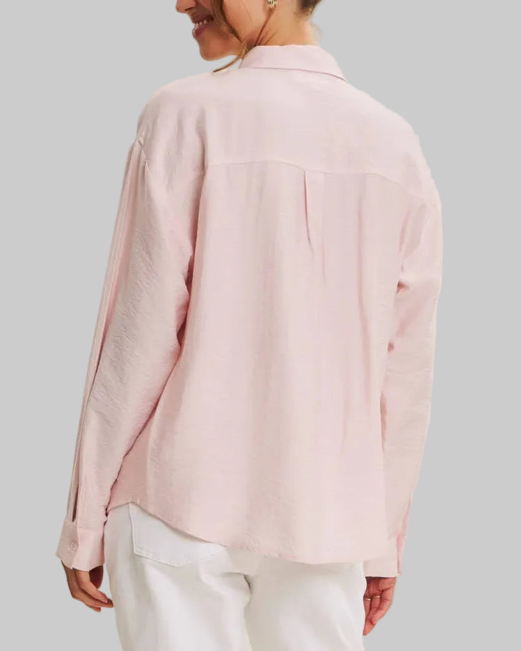 Person wearing a light pink blouse and white pants on a beige background