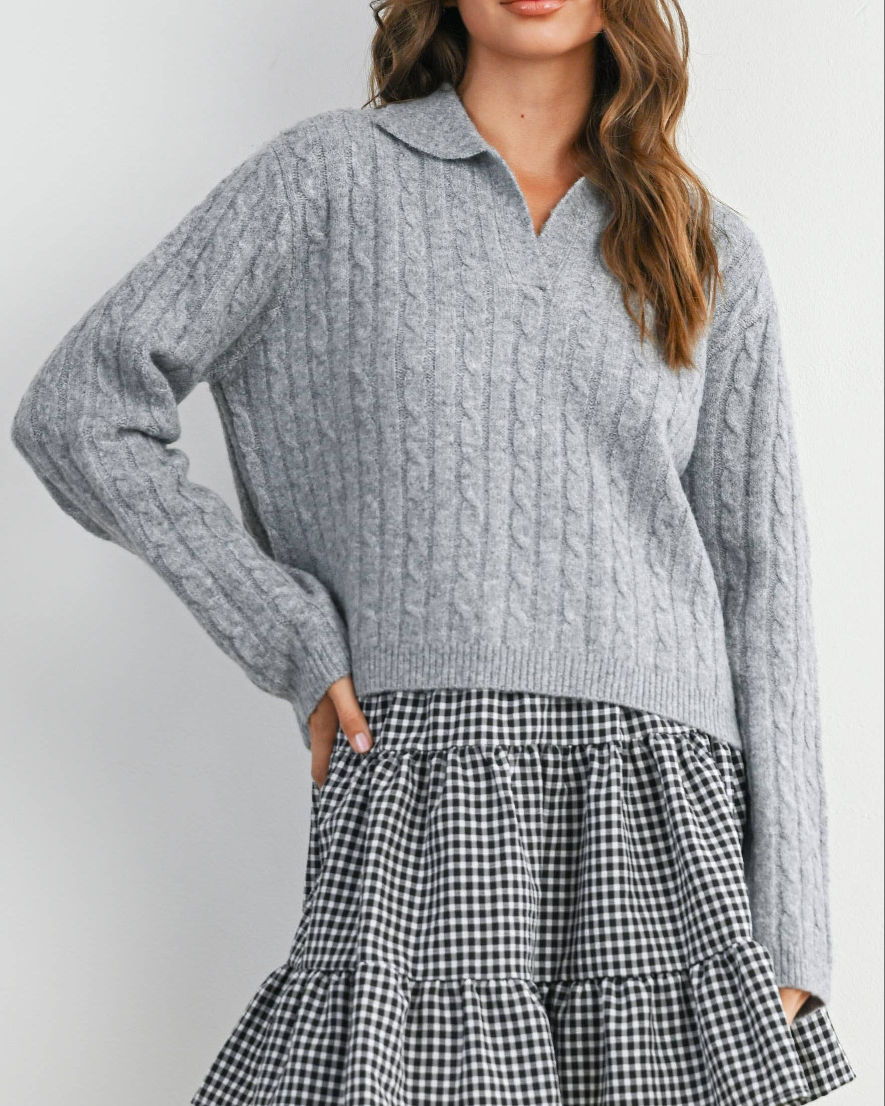 Woman wearing a gray sweater and black and white checkered skirt on a white background