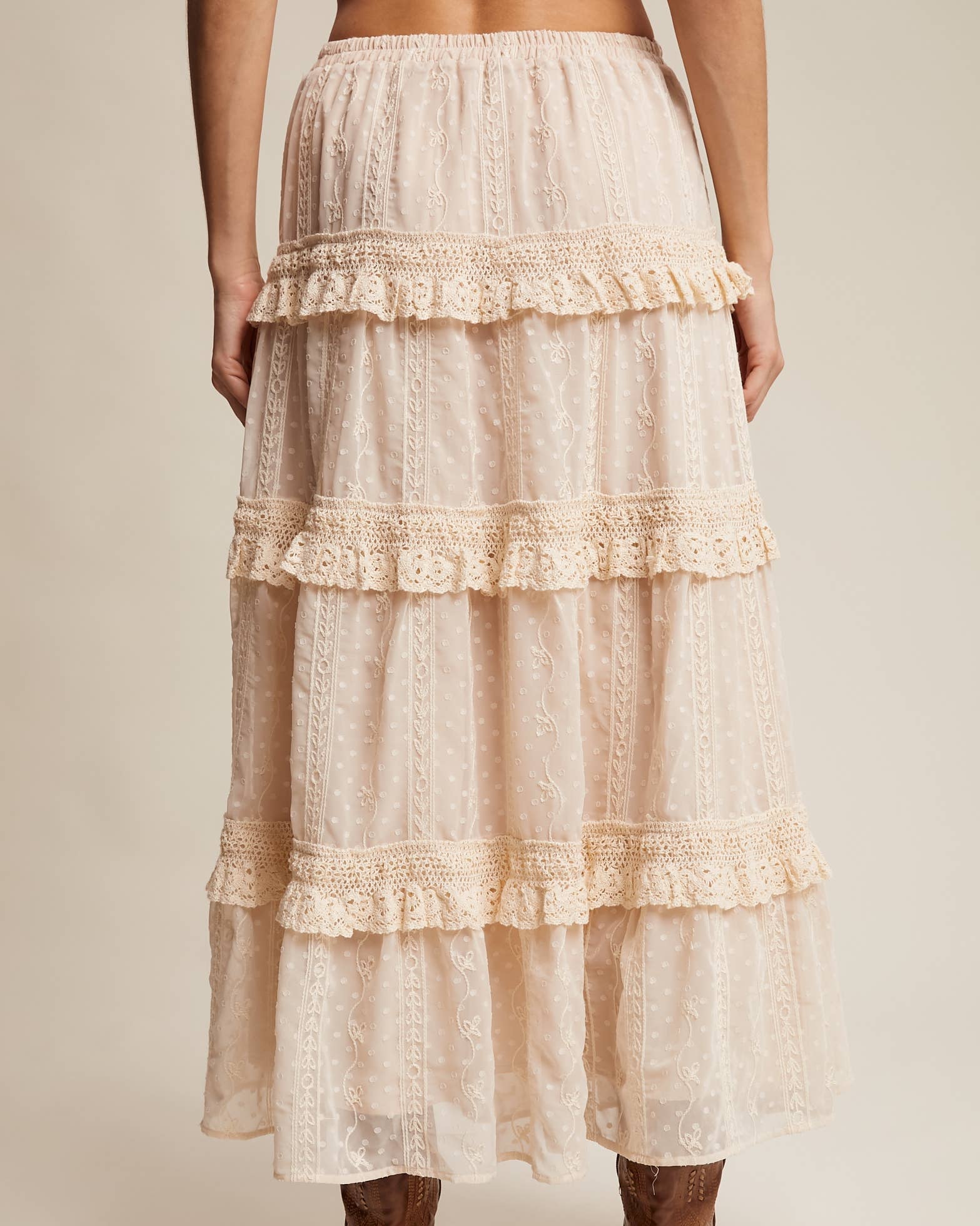 Long, tiered lace skirt worn by a person on a plain background