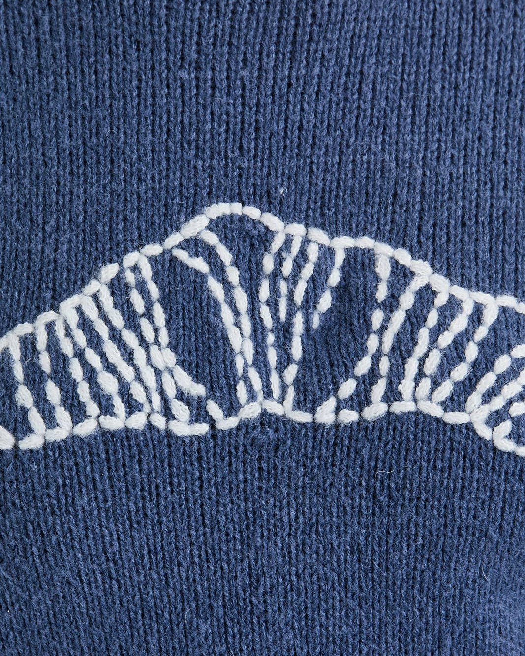 Close-up of a blue knitted sweater with white embroidered design